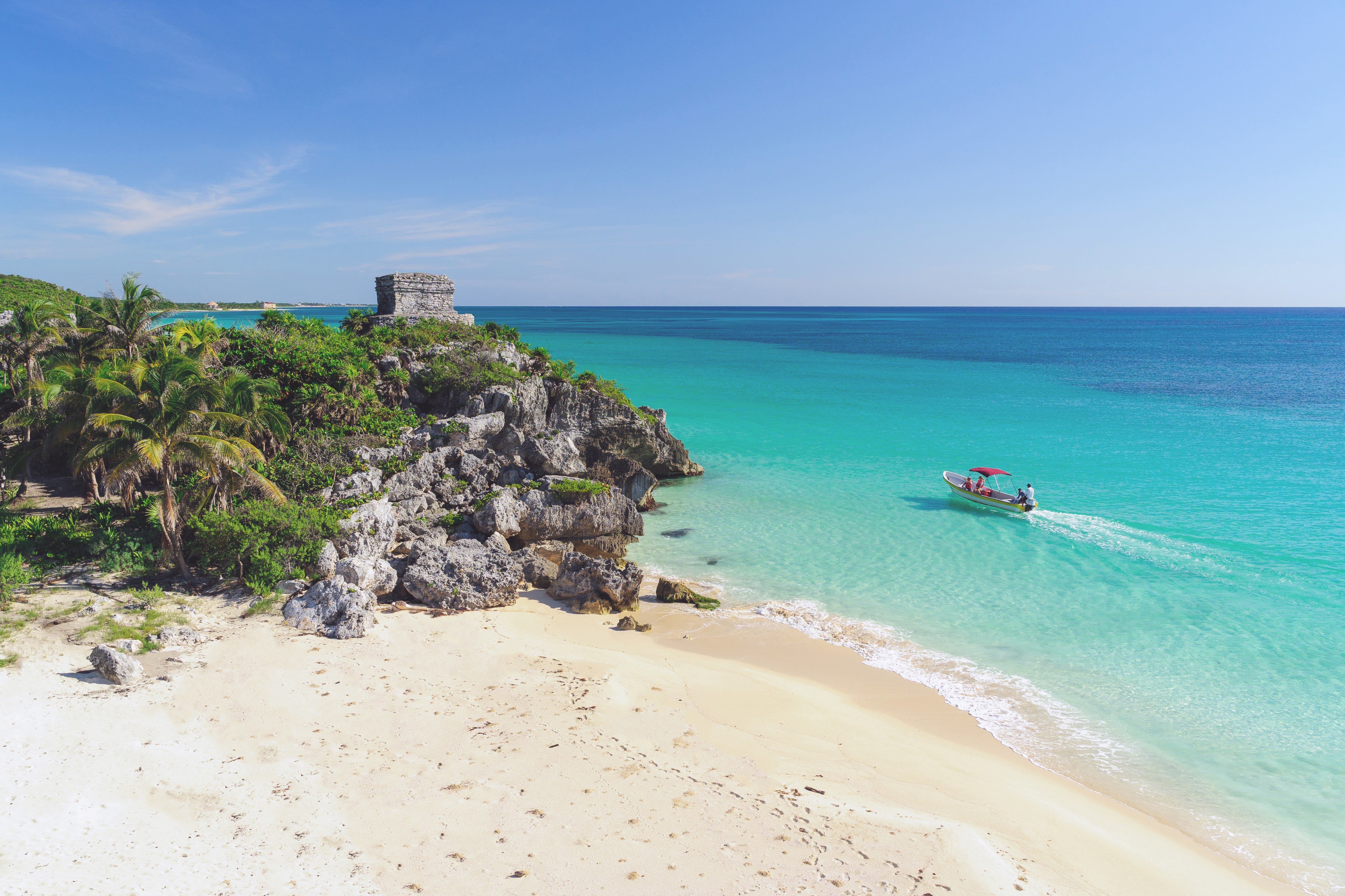 Mayan ruins on a seaside cliff overlooking a white-sand beach and turquoise waters in Tulum, Mexico 