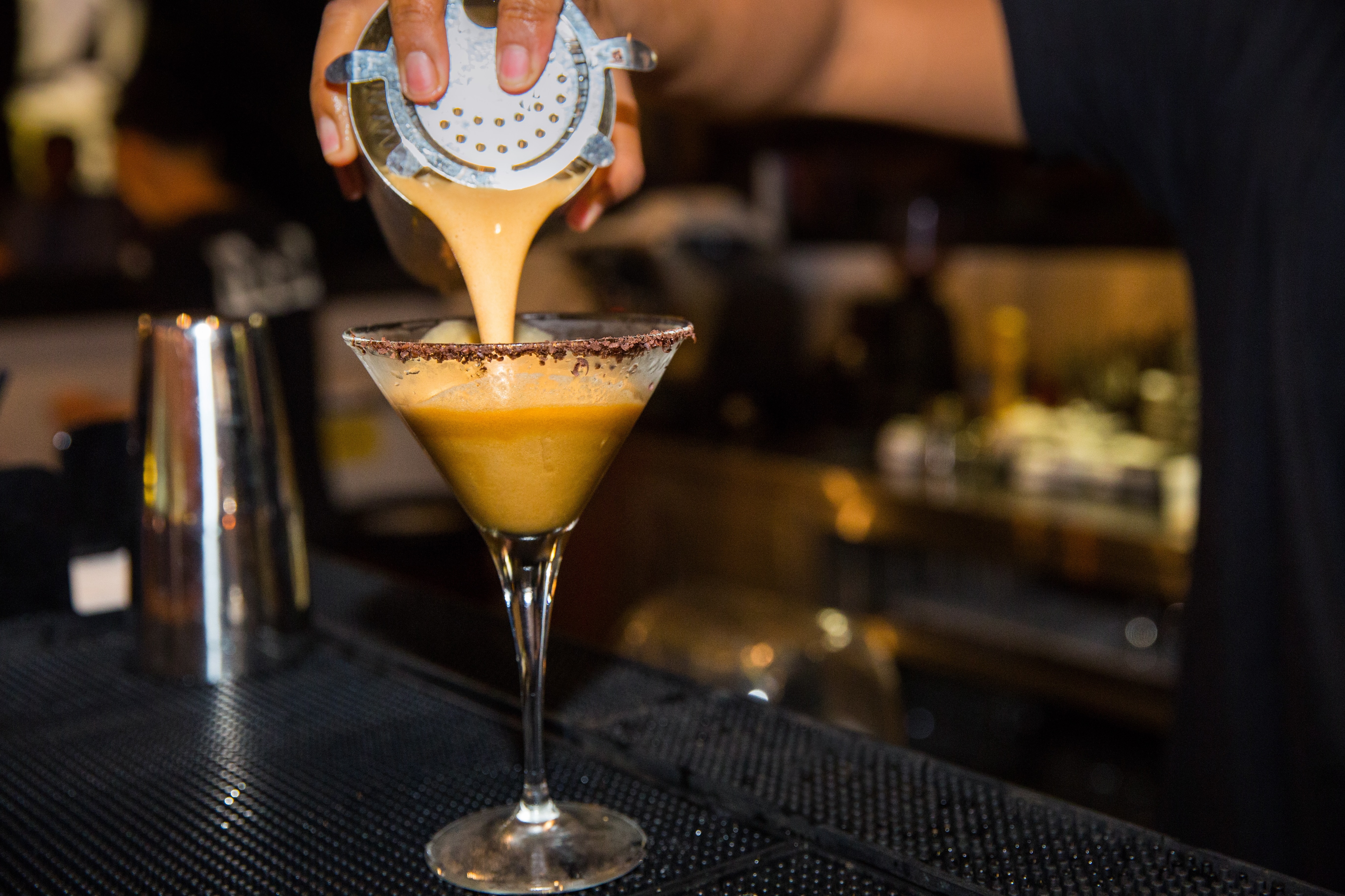 El barman vierte la bebida en una copa de martini