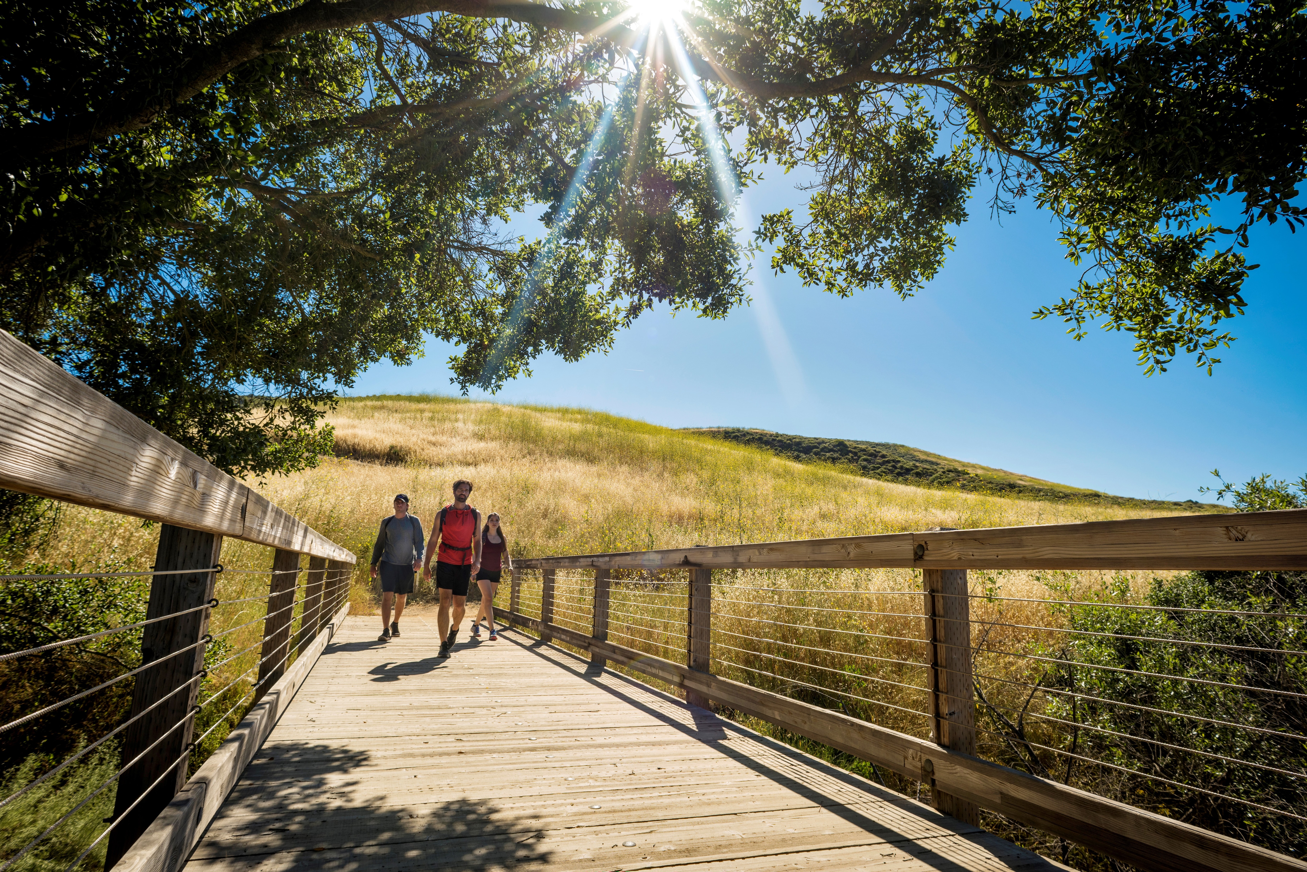 Three people walking on a bridge