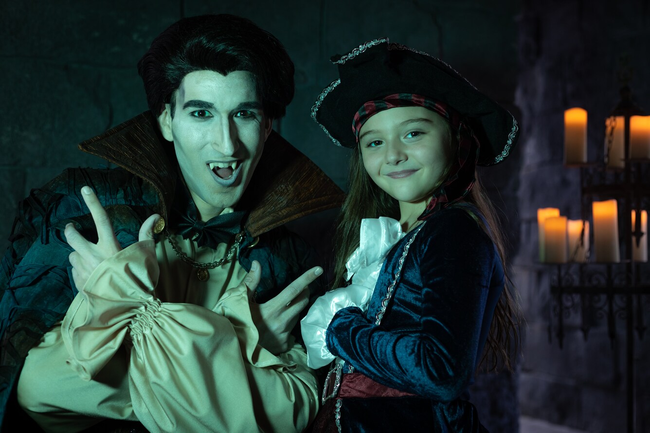 Actor dressed as a vampire posing for a photo with a child dressed as a pirate.