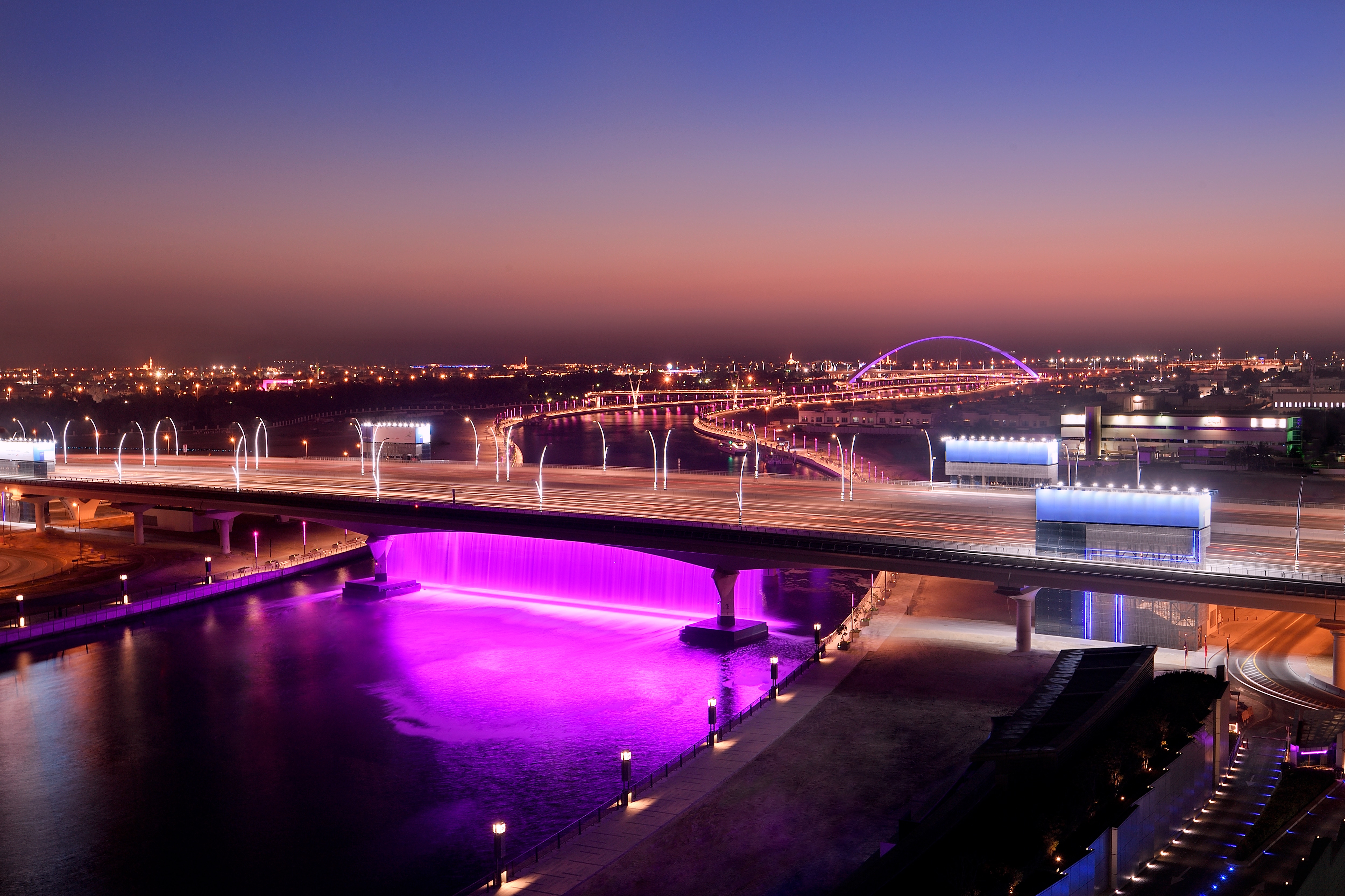 A bridge with a purple-lit water feature