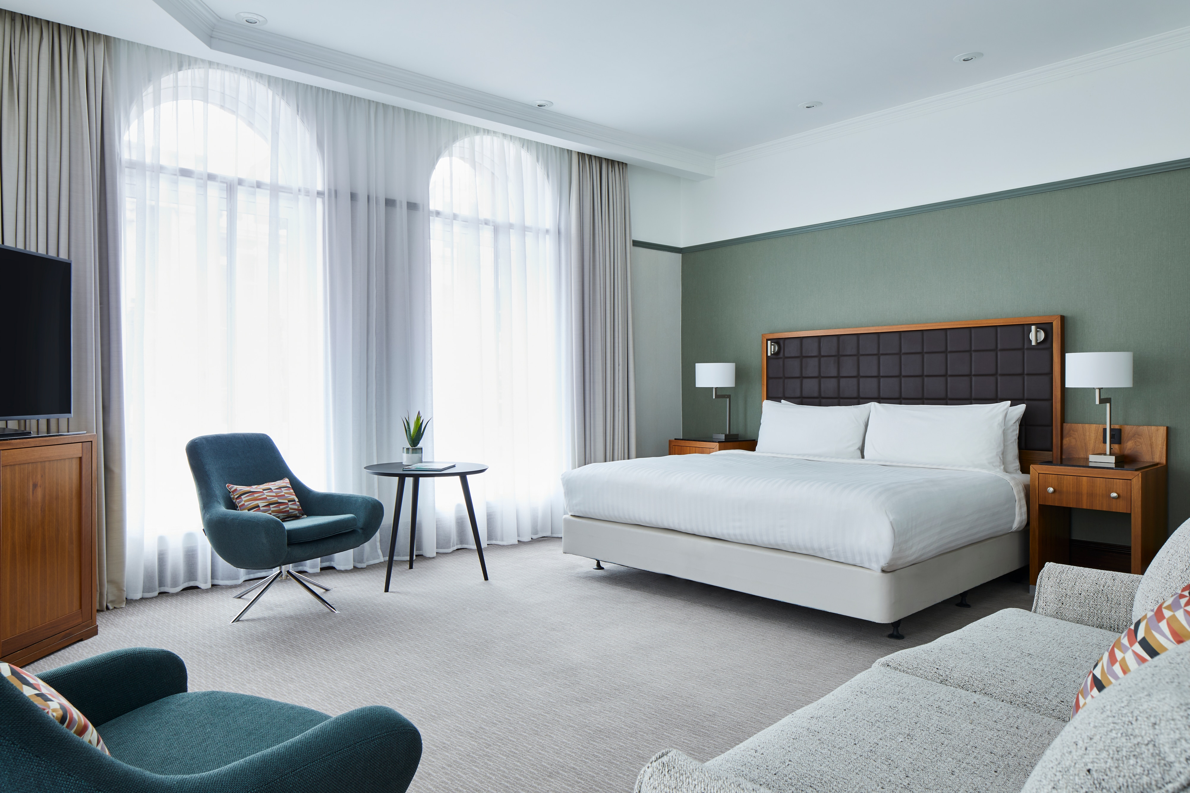 Room with bed, sofa, upholstered chairs and arched floor-to-ceiling windows