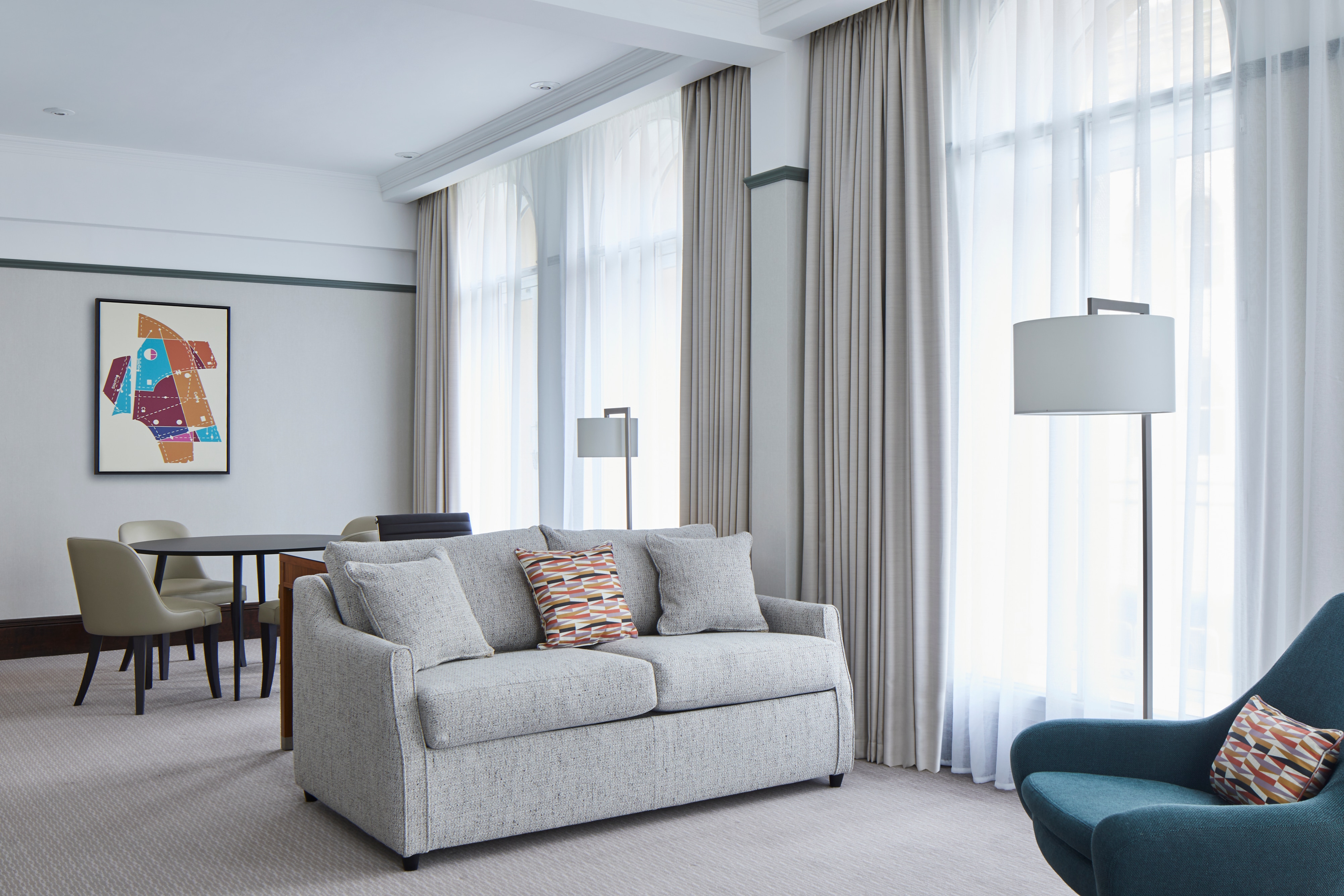 Room with arched floor-to-ceiling windows, sofa, upholstered chair and art on wall