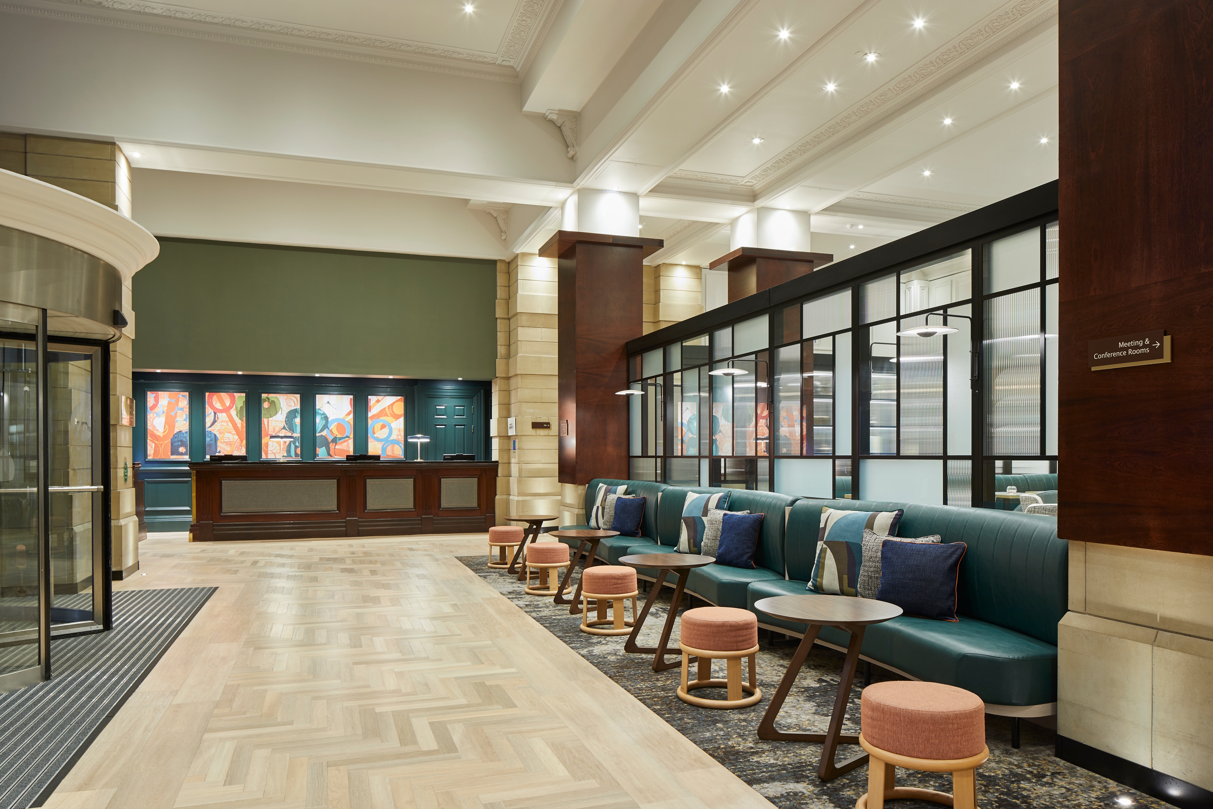 Lobby with upholstered bench seating along the windows, with throw pillows and small round tables