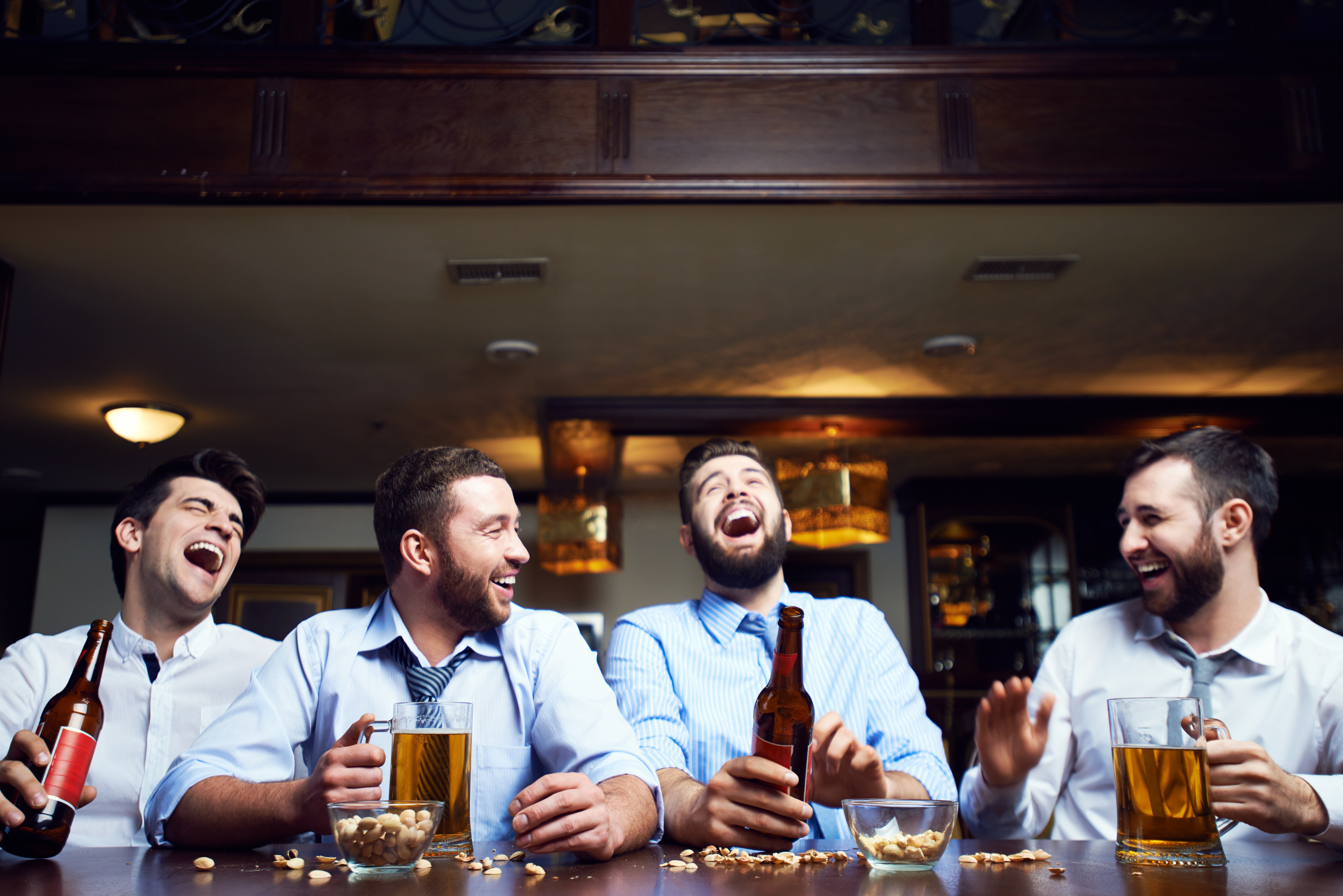Group men at bar laughing & drinking