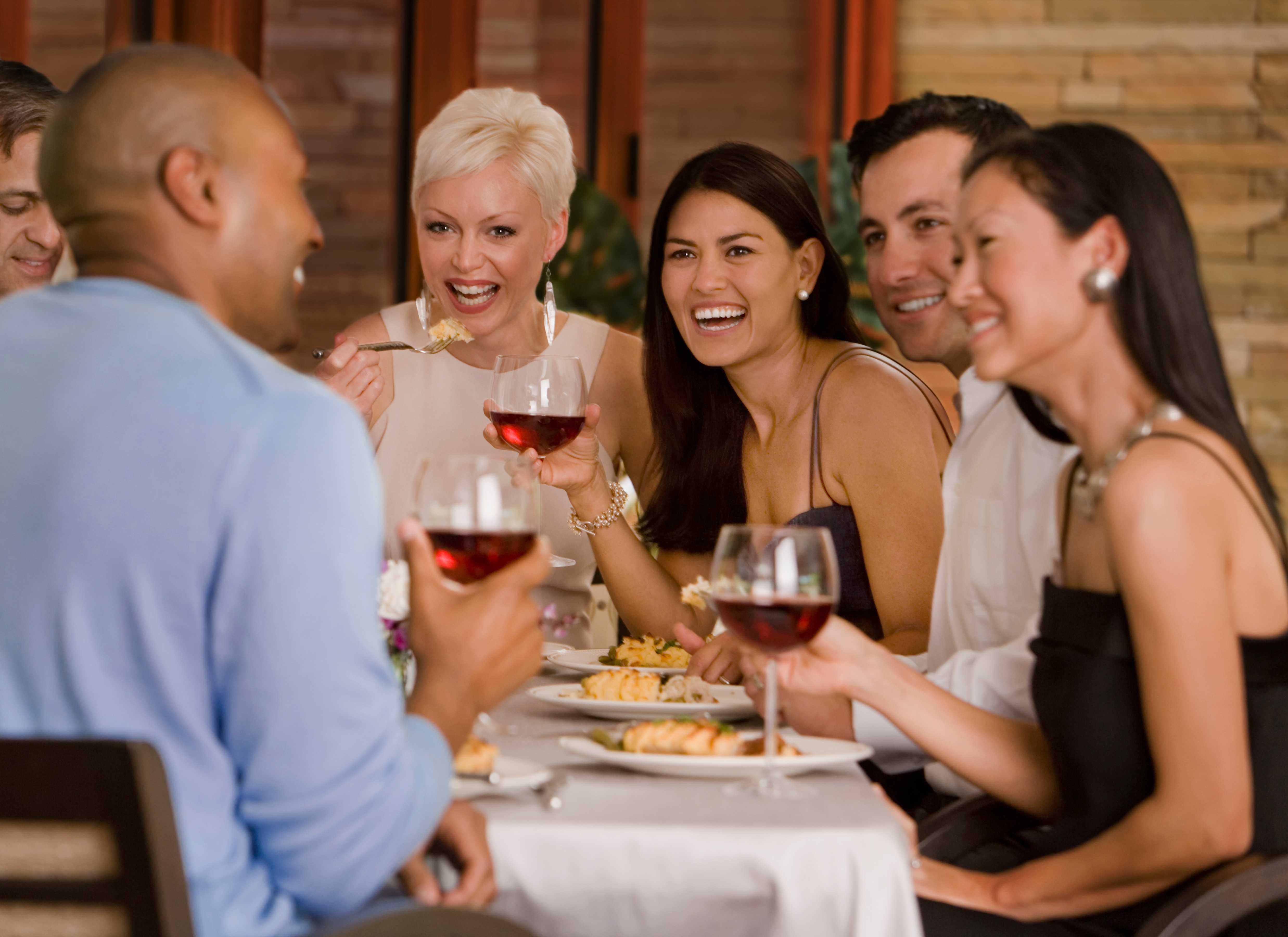 Group of people at table laughing & drinking