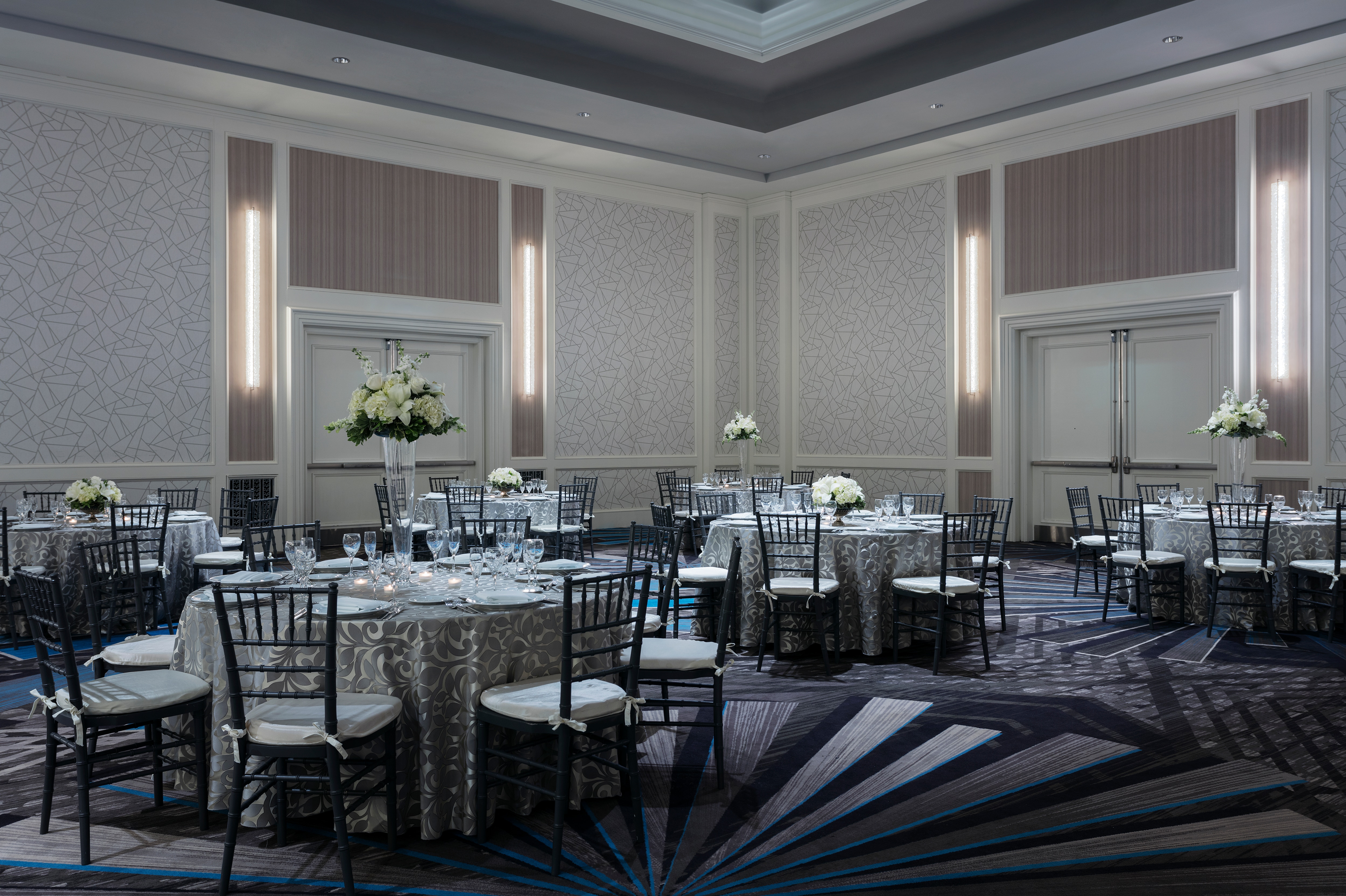 Ballroom set with round tables with white flower arrangements