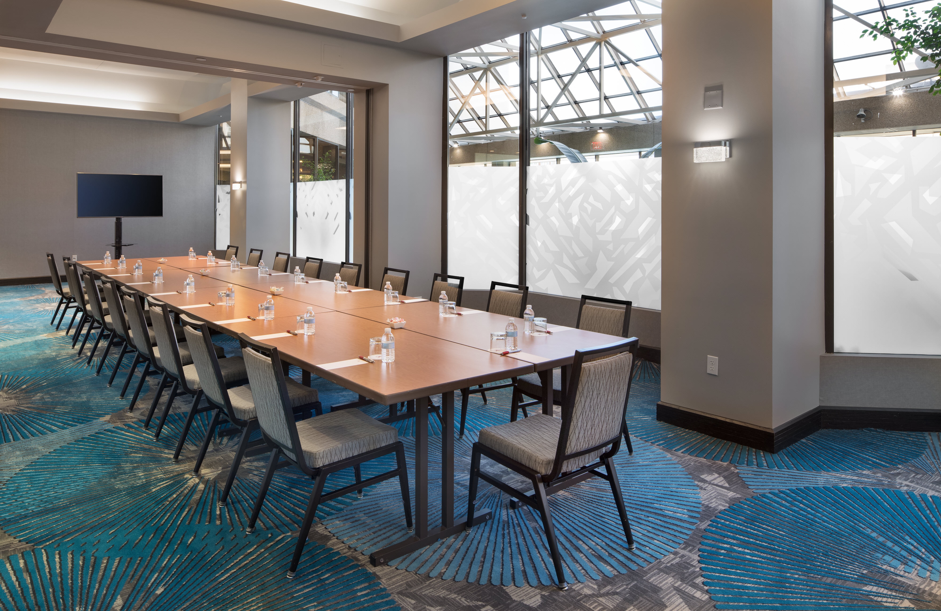 Long table and flatscreen in room with large windows frosted on lower half