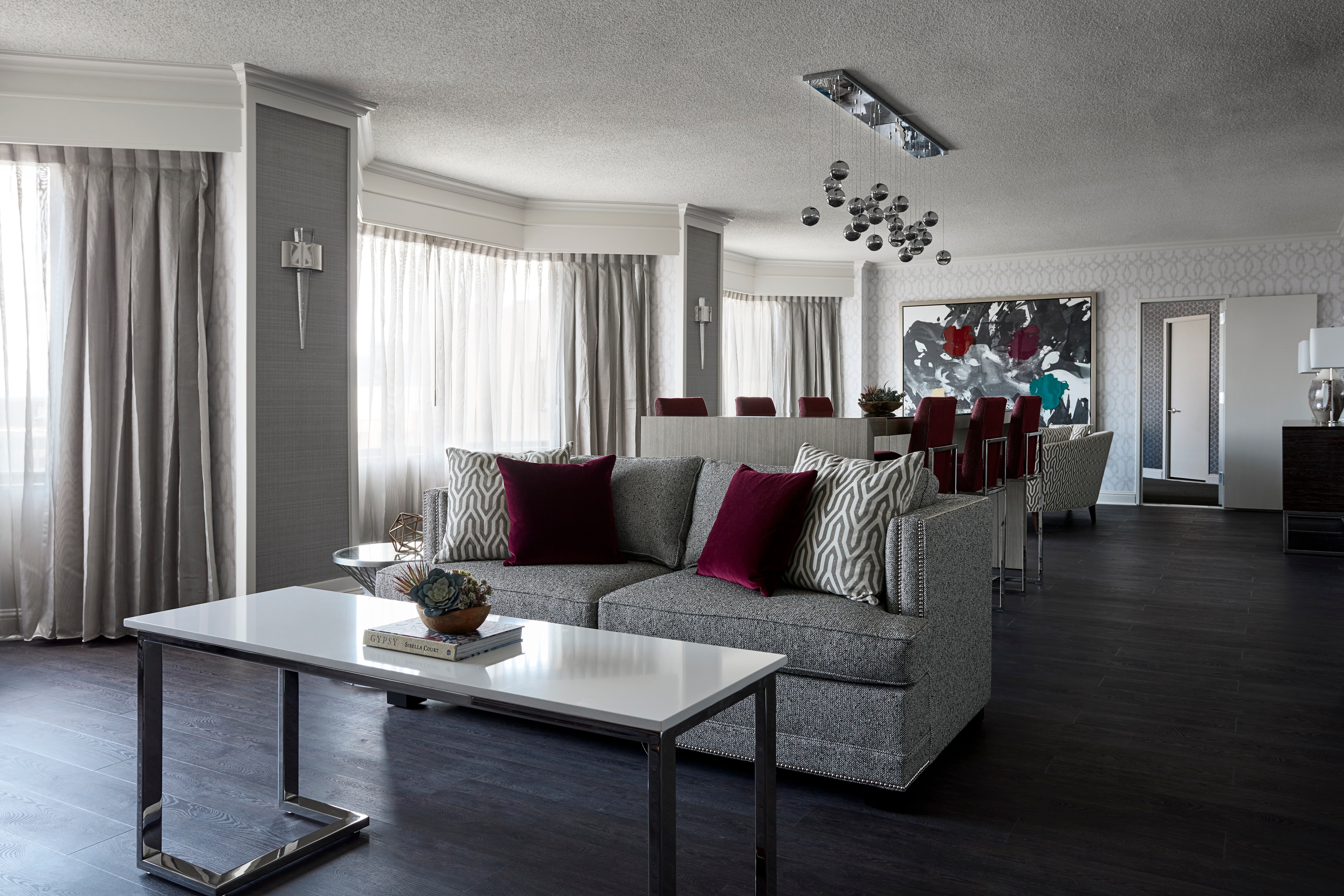 Gray-and-red room with sofa and high dining table with modern chandelier