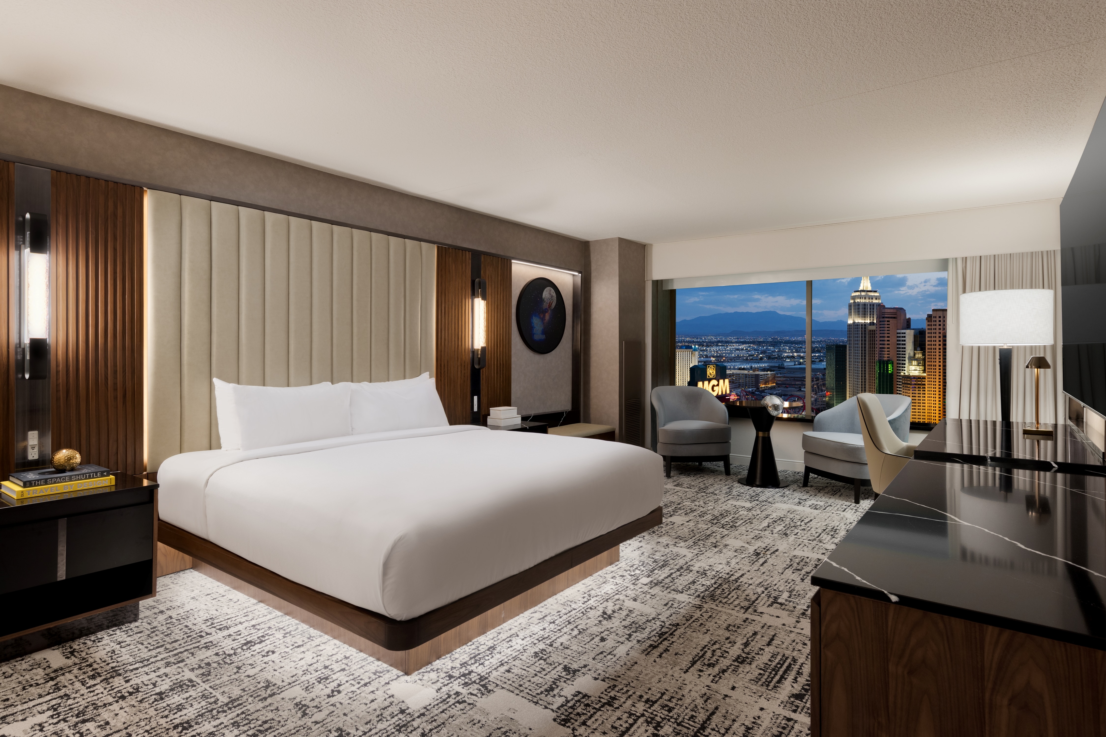 Nightstand, bed, seating area, window view.