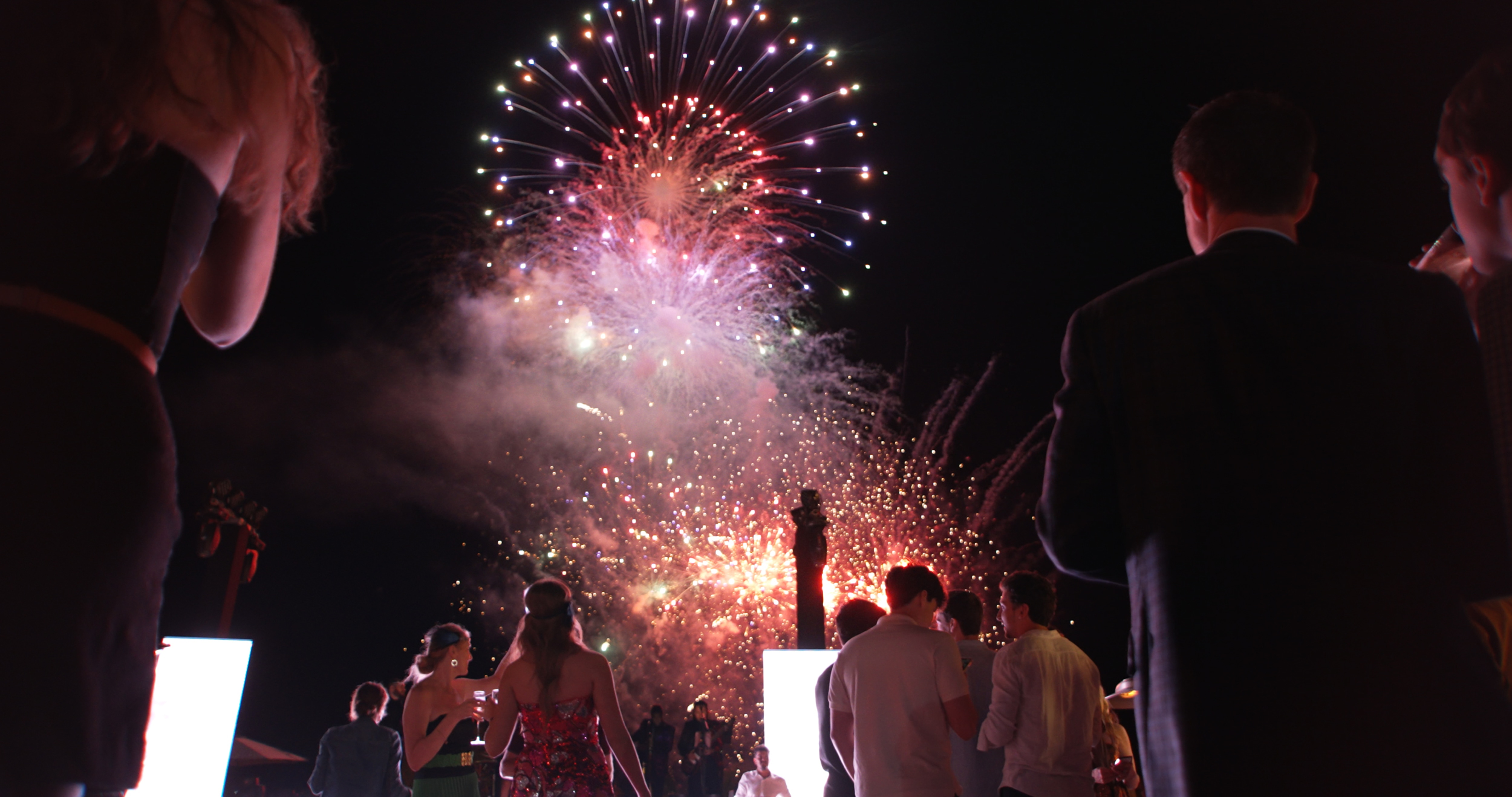 Gente mirando los fuegos artificiales en el cielo nocturno