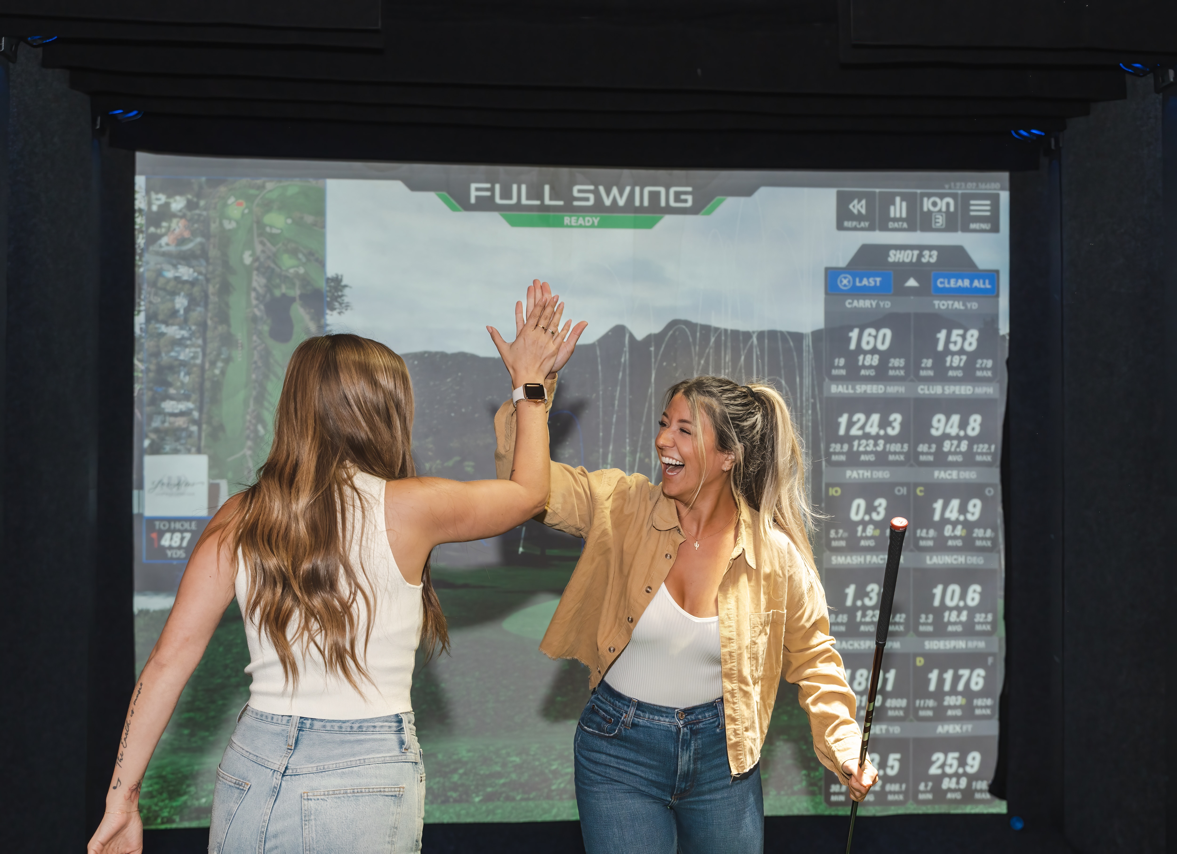 People high fiving in the Topgolf swing suite