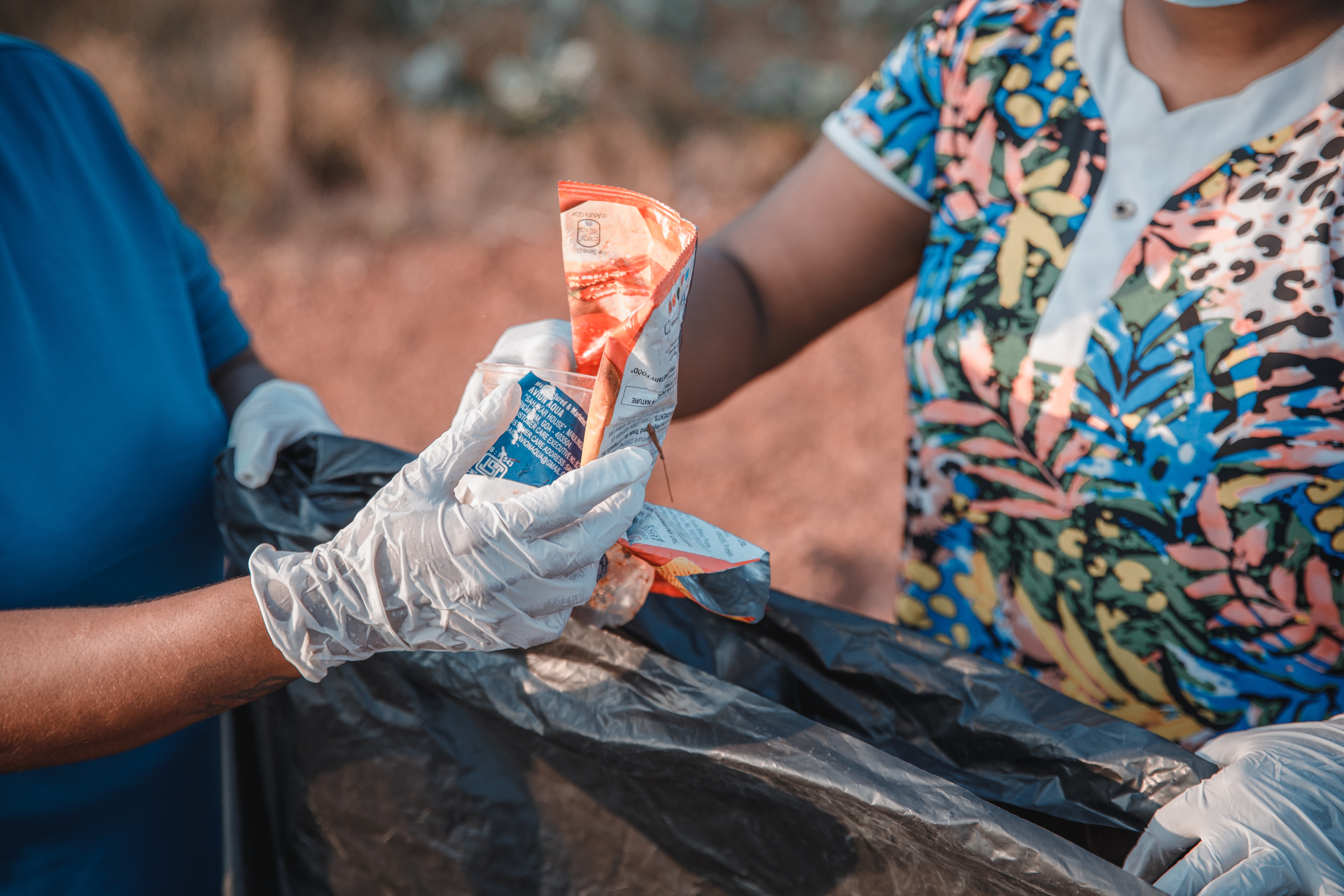 Person putting litter in a trash bag.