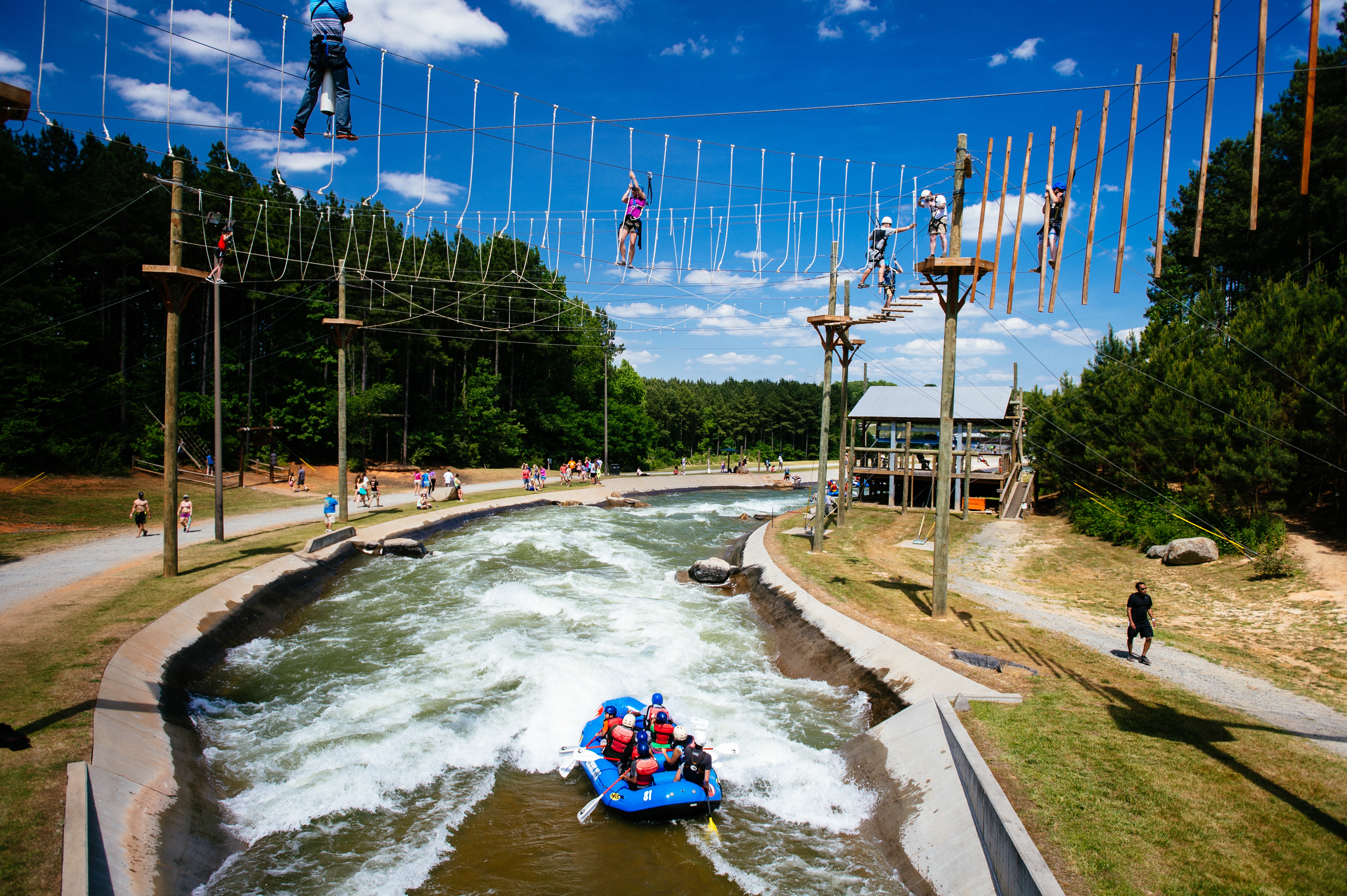 People whitewater rafting and using a challenge course at a whitewater park