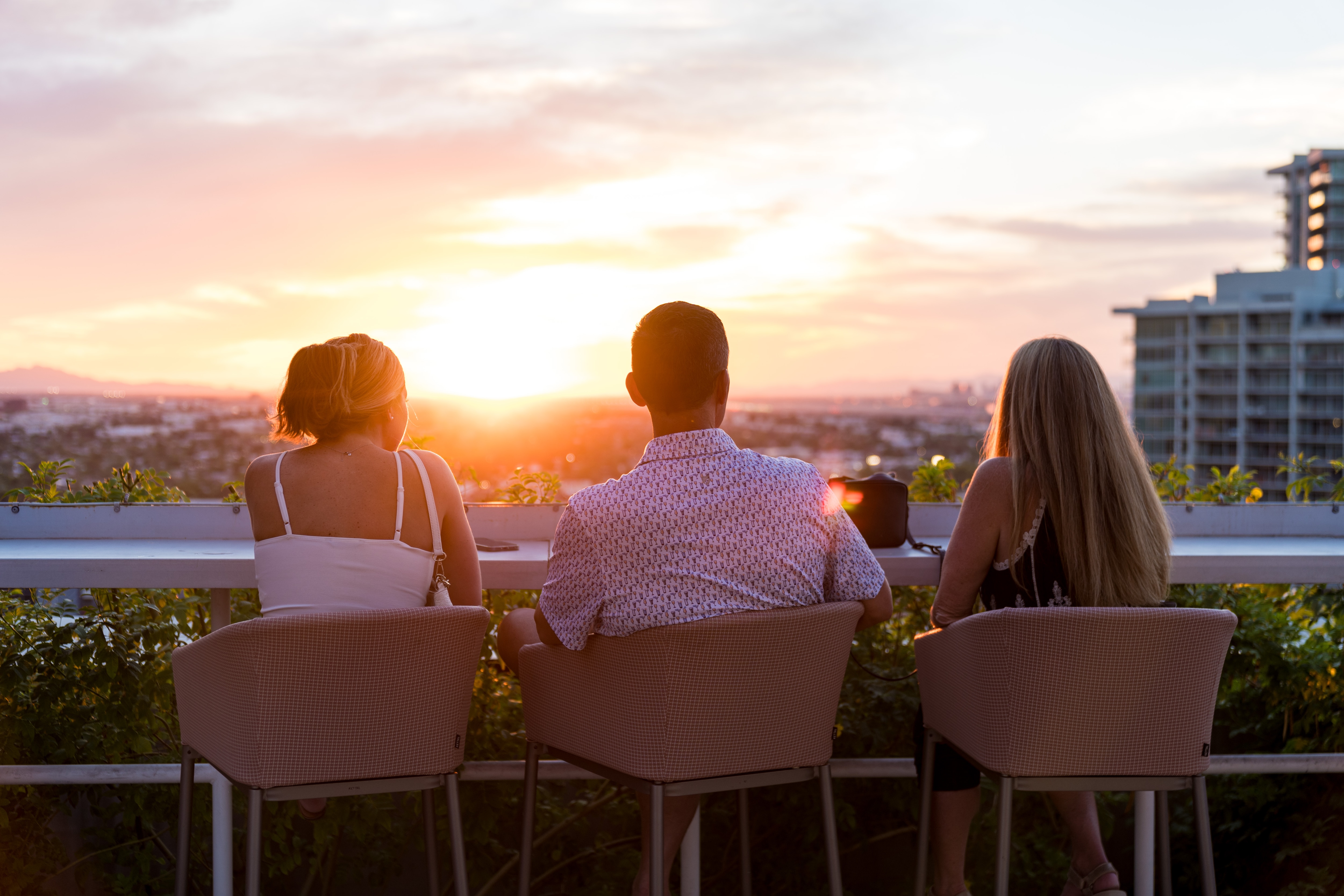 3 people enjoying sunset on a rooftop