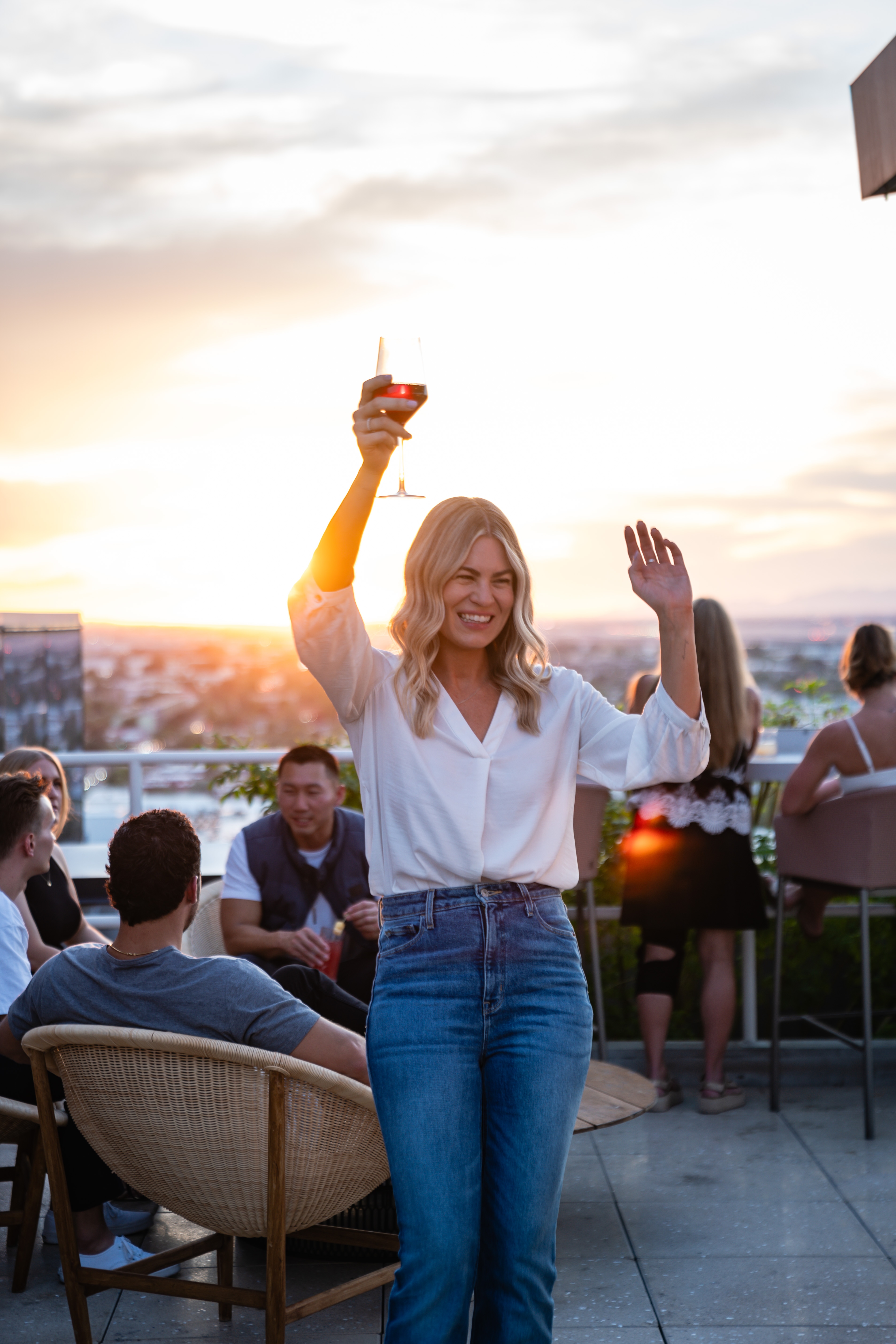 Woman dancing at rooftop bar with drink. 