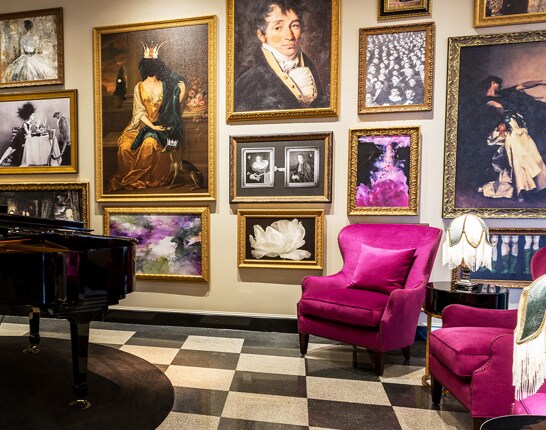 The Raleigh Room with piano, bright purple armchairs, and historic-themed portraits on the walls