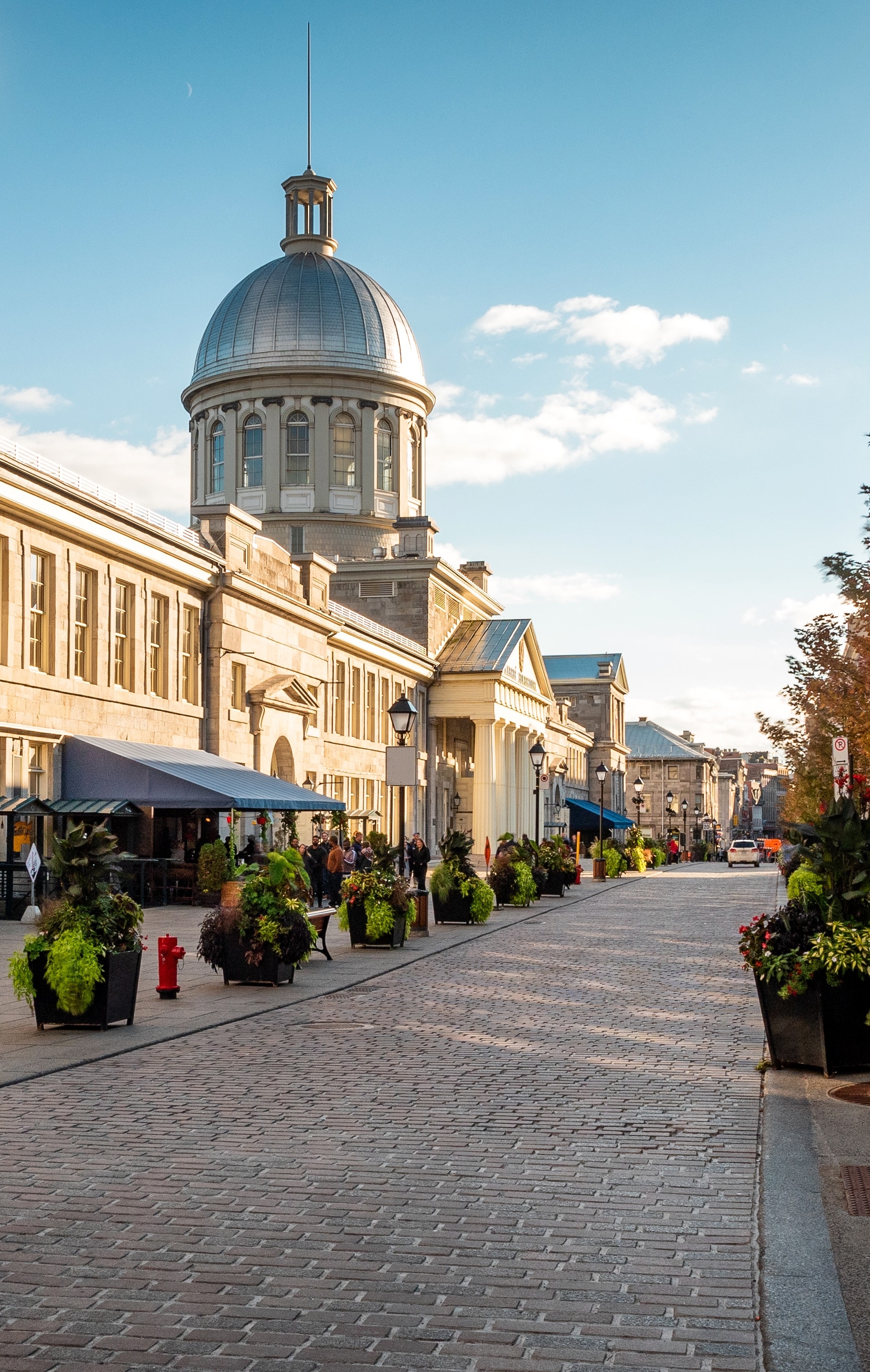 A cobblestone street in Montreal in Quebec, Canada, with the two-story, domed Bonsecours Market rising beyond 