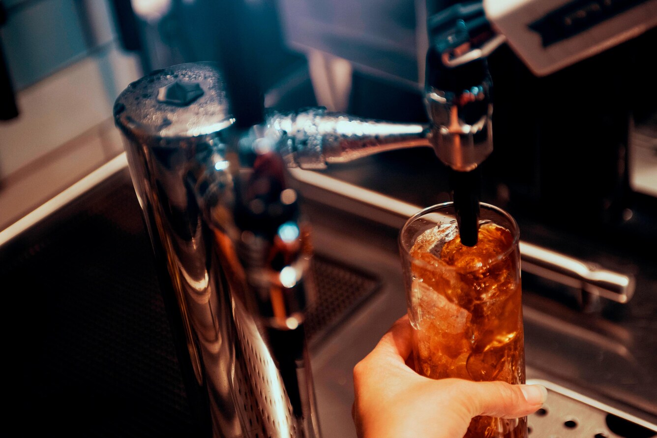 an iced glass being filled with iced coffee