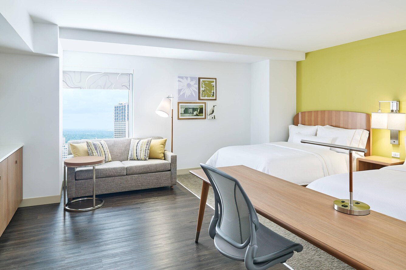 Guestroom featuring two queen beds, a couch and desk with a window