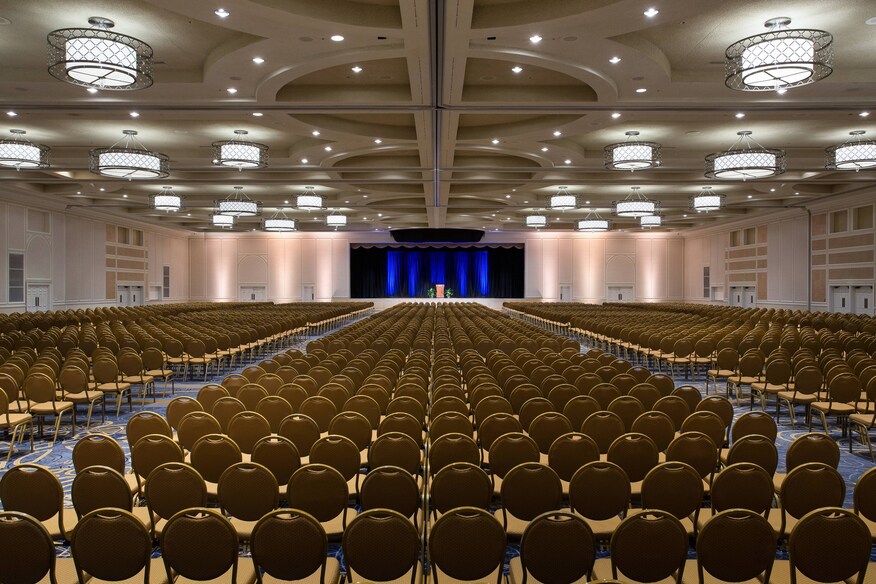 Large ballroom with hundreds of seats facing a lecturn and a large screen.