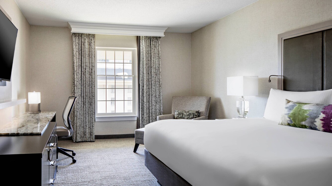 guest room with bed and window looking towards atrium.