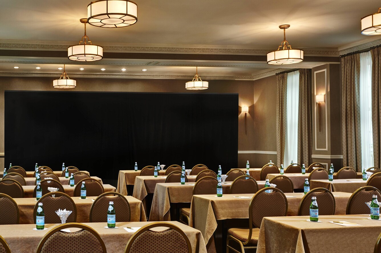 Large conference area with long tables and chairs facing a screen at the front.