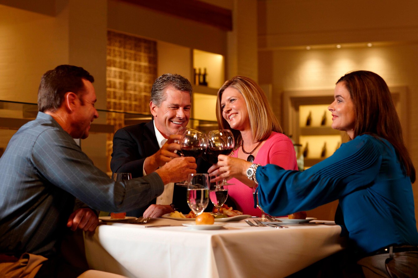 Group of people toasting at a table with wine glasses.