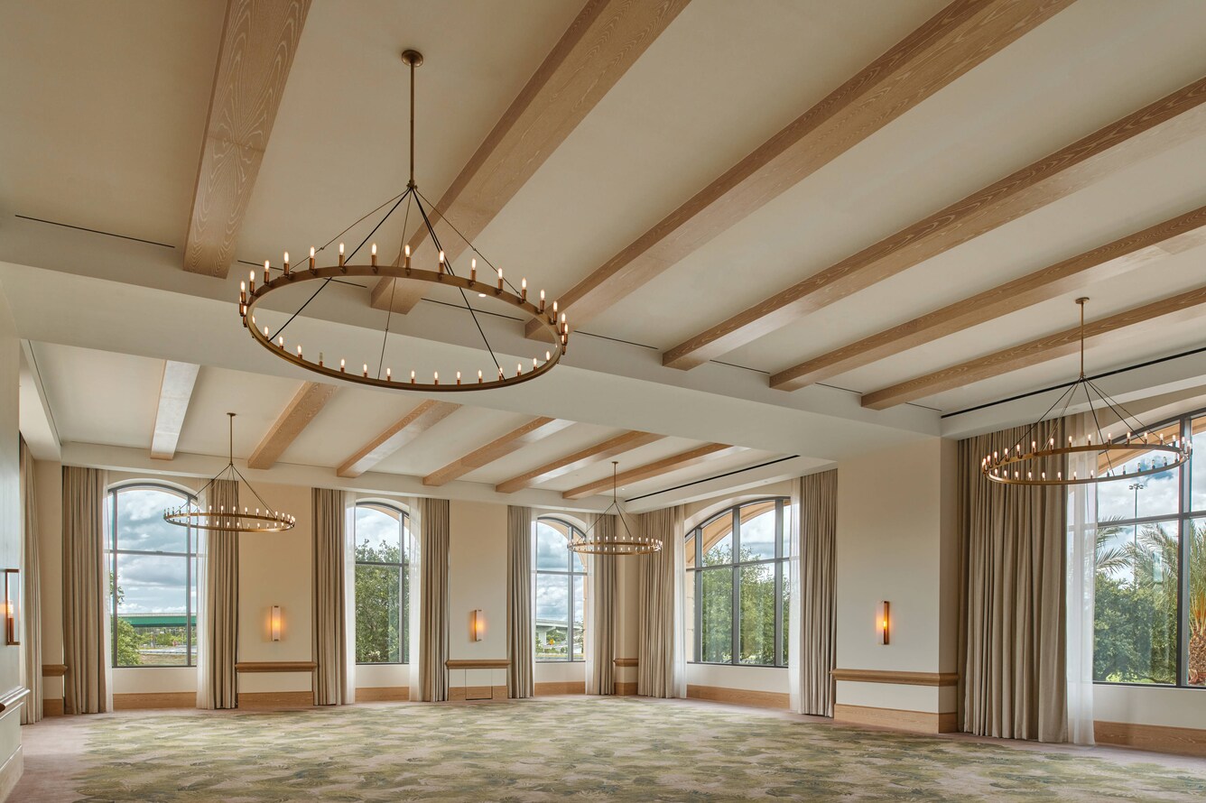 Meeting room with patterned carpet, large windows, chandeliers, and wooden ceiling beams.