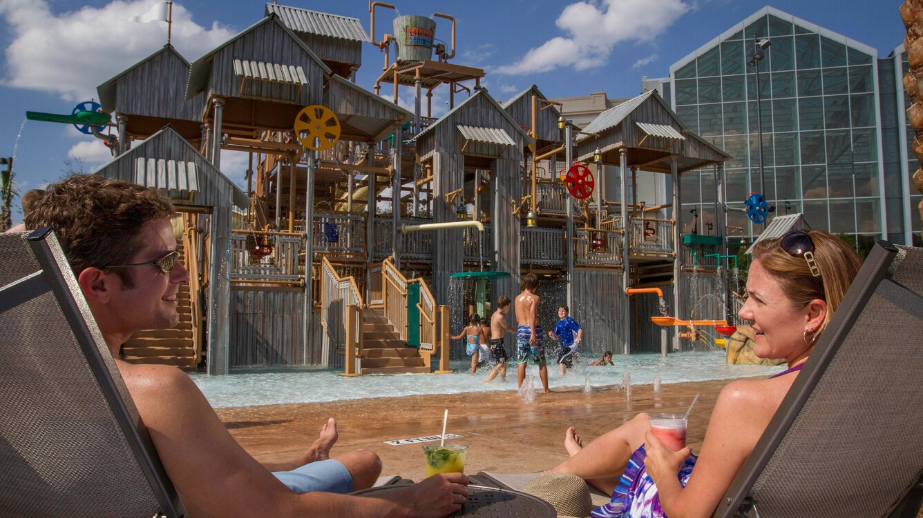 Man and woman in beach chairs beside the splash pool.