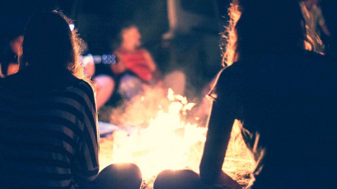 Silhouette of children sitting in from of an open campfire