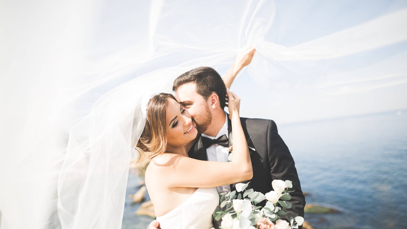 Couple enjoying their new union posing infront of the lake on a sunny day