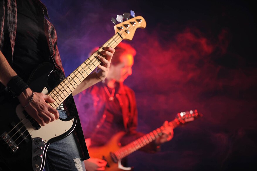 Musicians playing guitars at a show on stage with a red light
