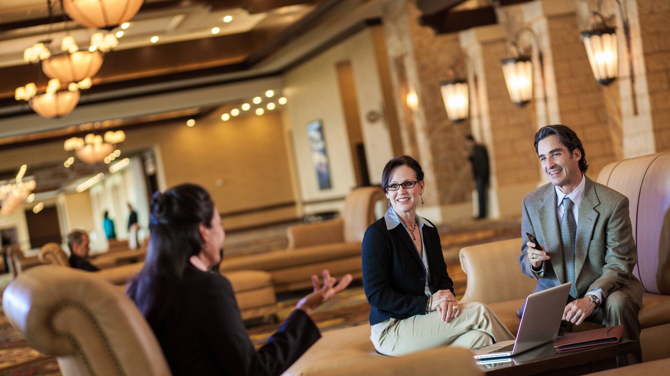 Pre event gathering with a couple of people in a large prefunction space with lounge seating.