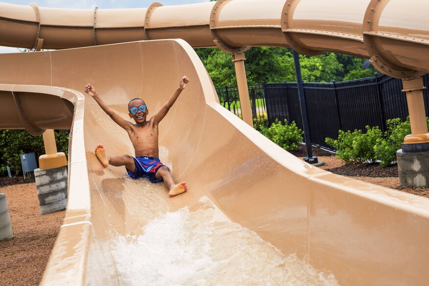 kid sliding down waterslide with arms raised in excitement