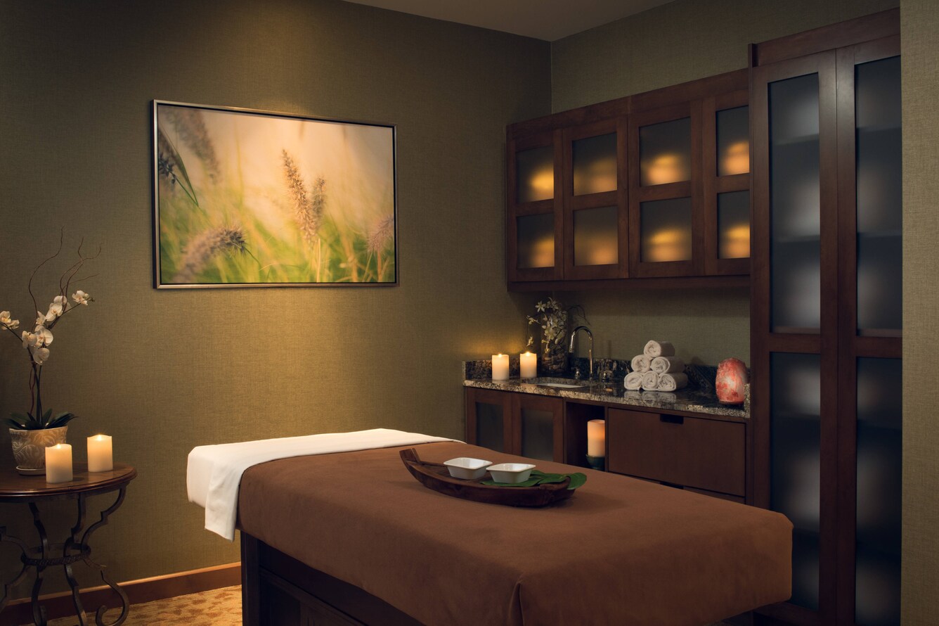 Massage table with tea light details and oils on top of sheets