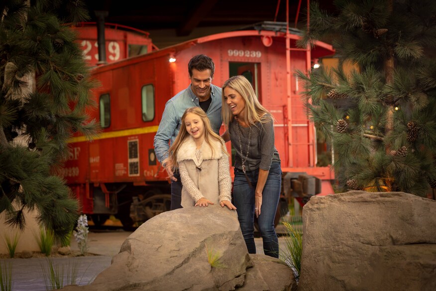 Man, woman, and child in front of a caboose.