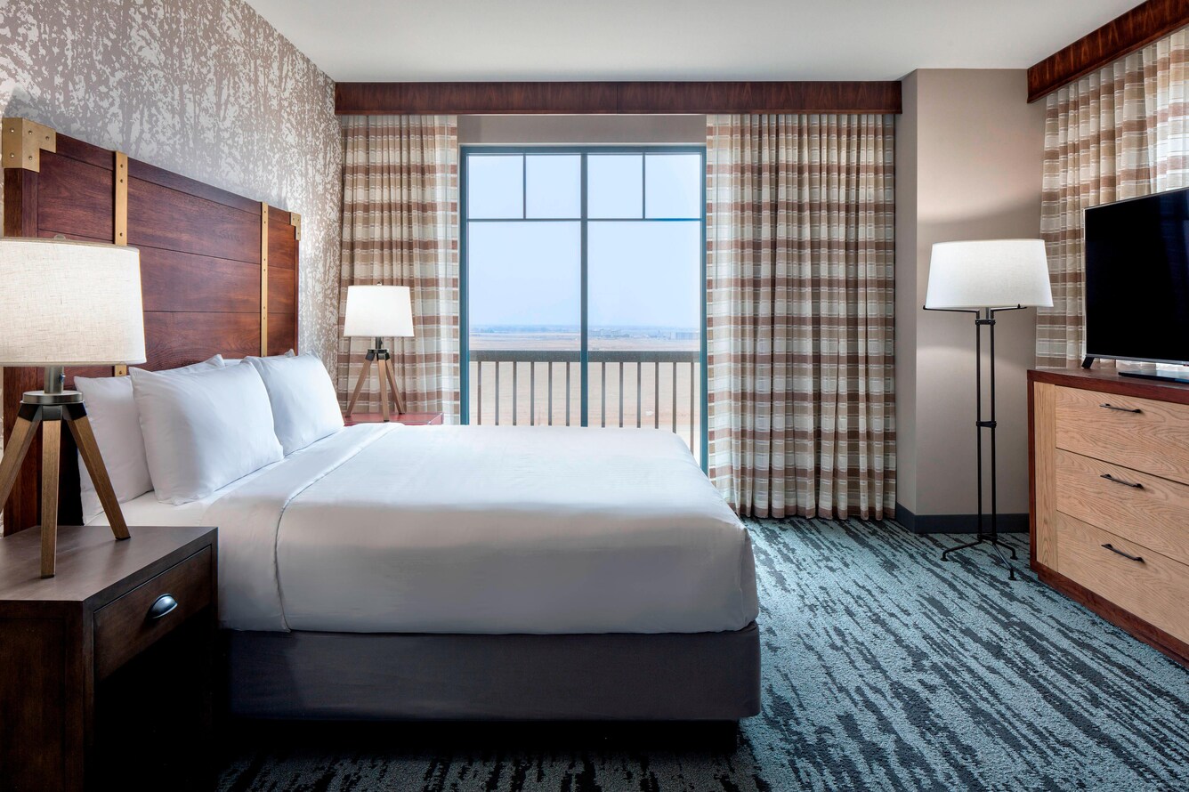 A single king bed in the Deluxe Suite with a flat screen tv and tv stand.