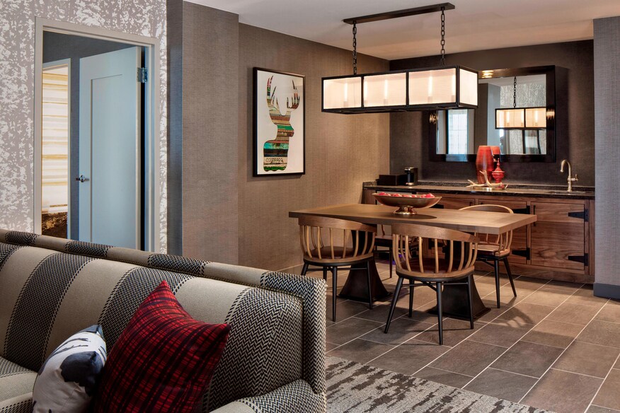 Suite dining table and chairs on a tiled floor with a partial view of the sofa.