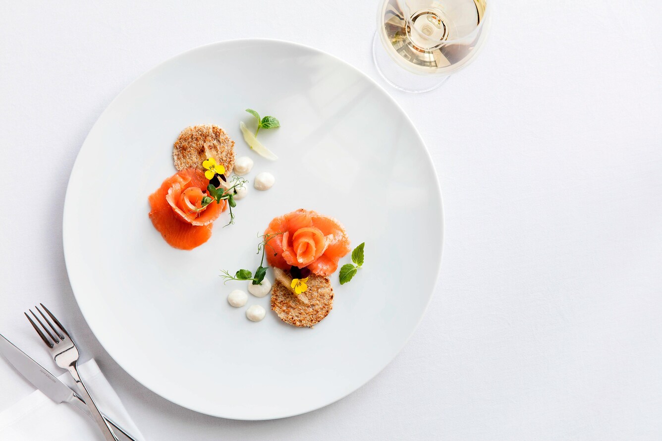 Overhead view of white plate with colorful pastes and garnish with a glass of wine