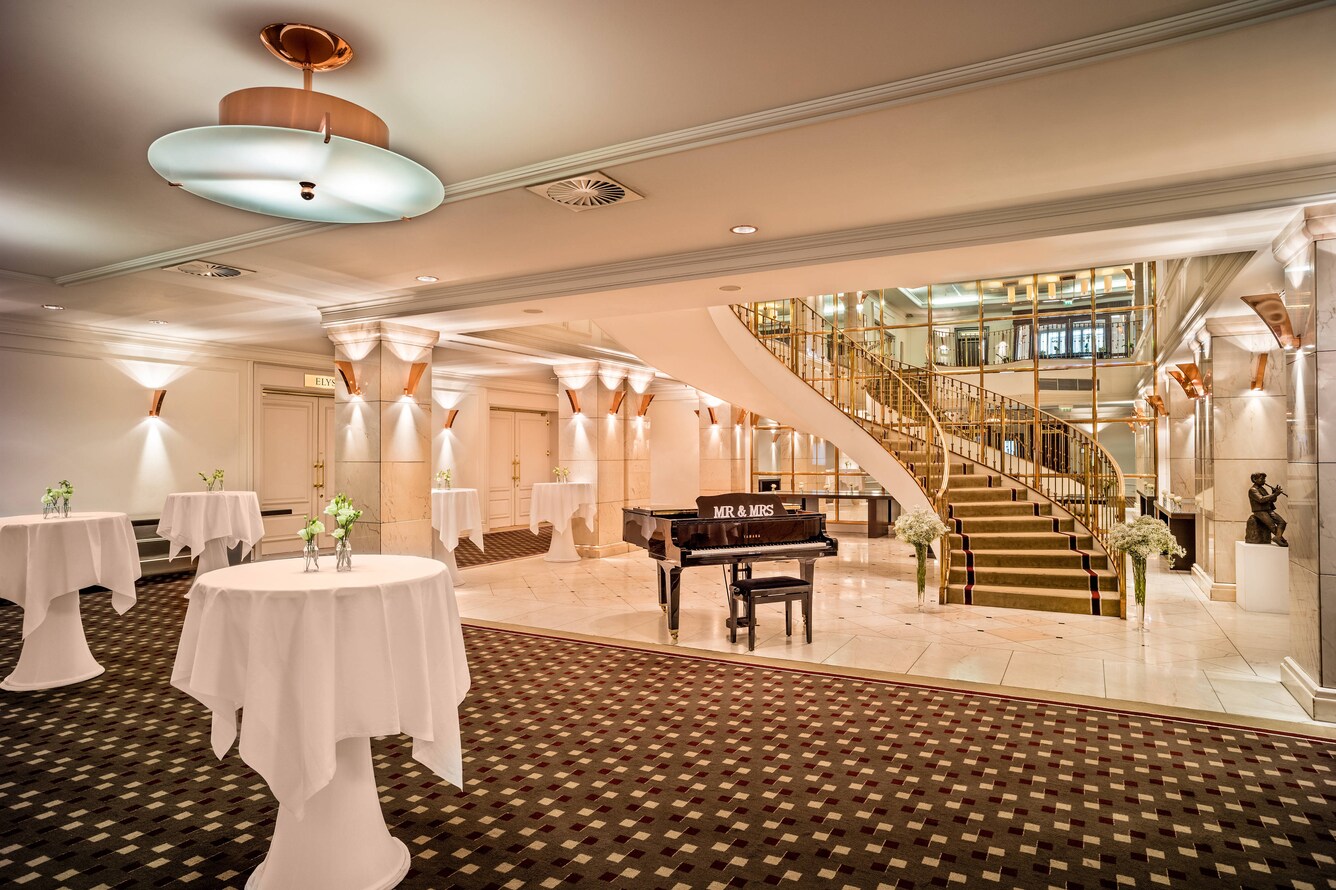 foyer with standing table, piano, and staircase