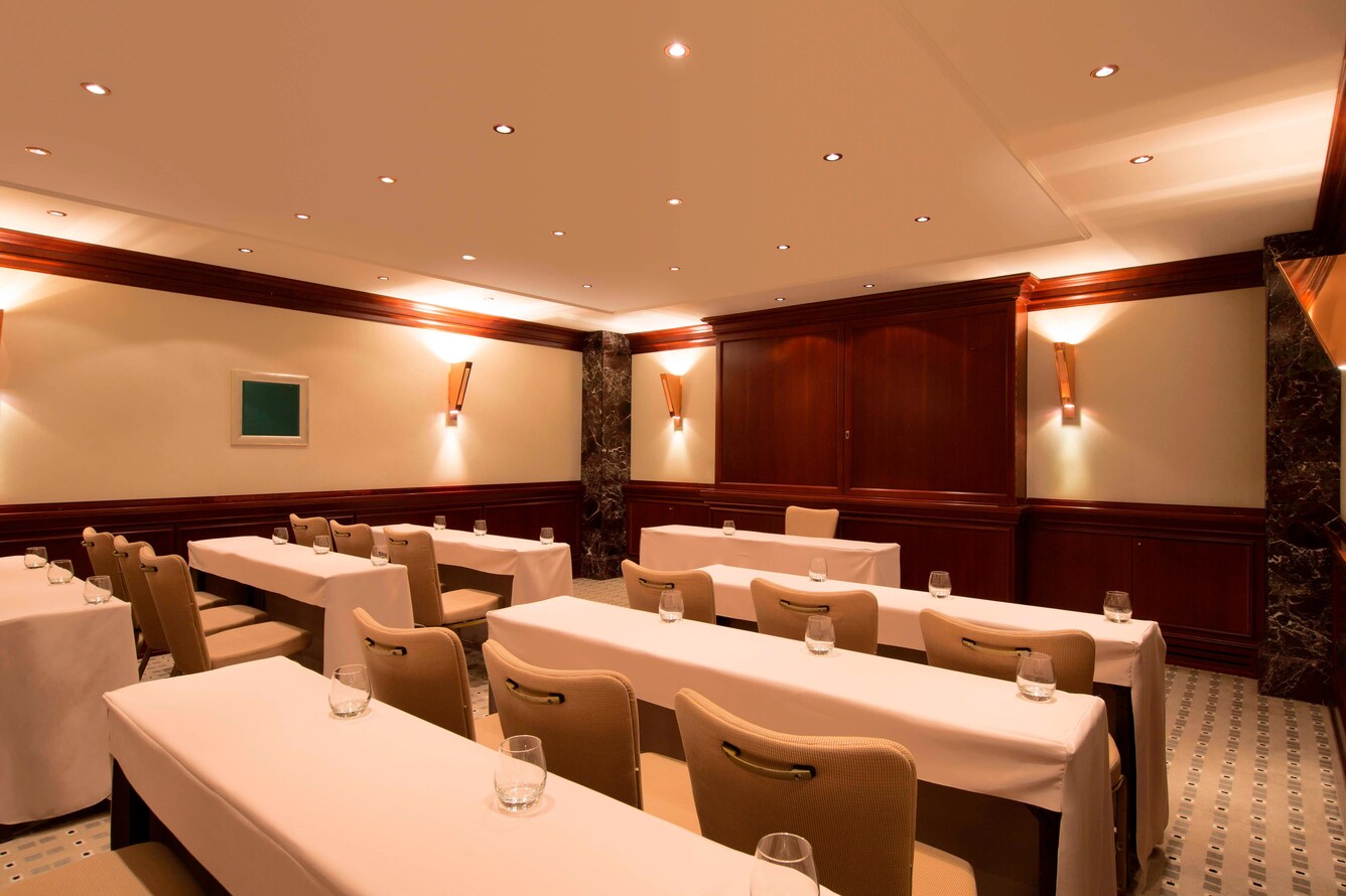 Small conference room with long tables and chairs facing towards a lecturn