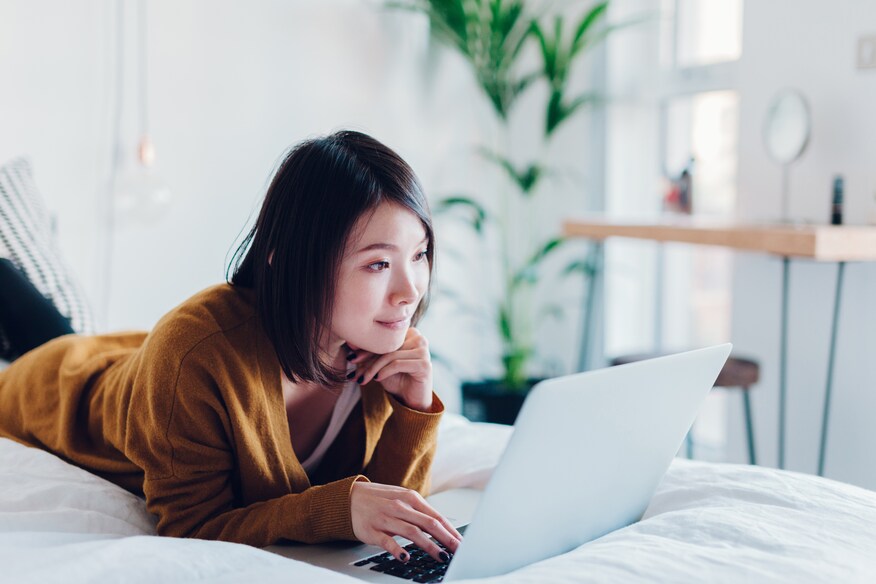 Woman laying on bed with laptop