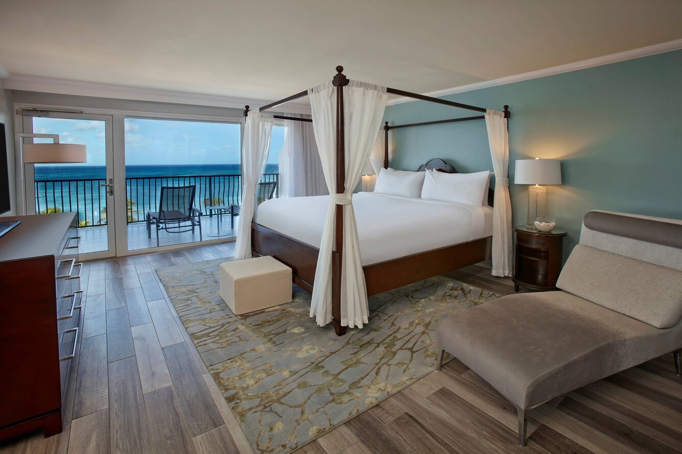 Governor's suite four poster king bed with a view of the balcony and ocean.