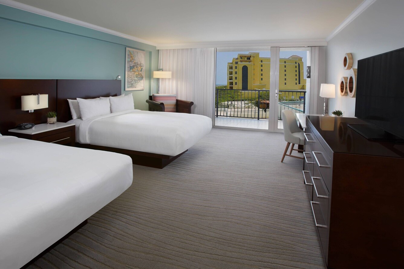 Guestroom with two queen beds and view of a hotel.