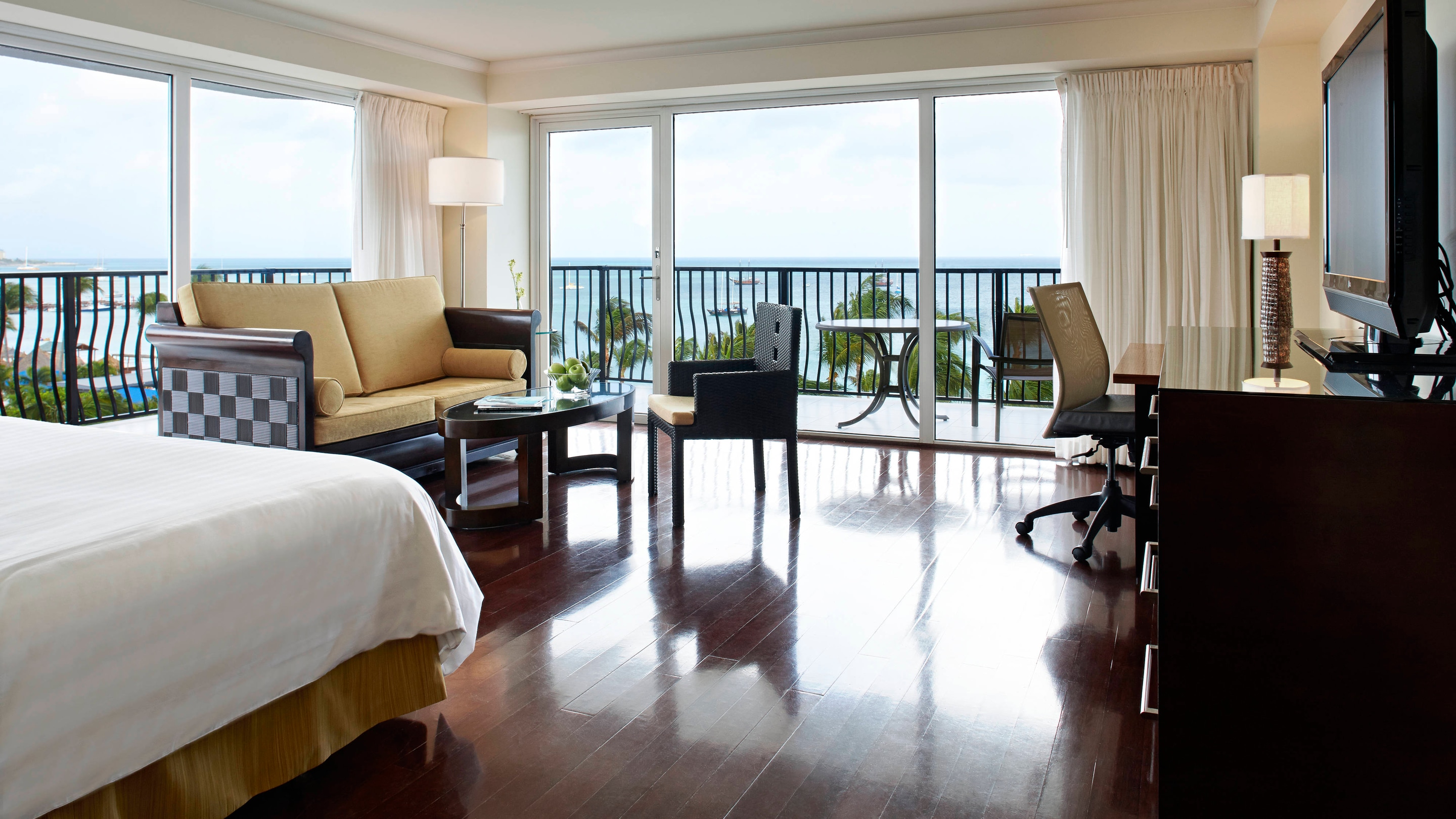 Suit living area with hardwood floors assorted furniture and a view of the balcony.