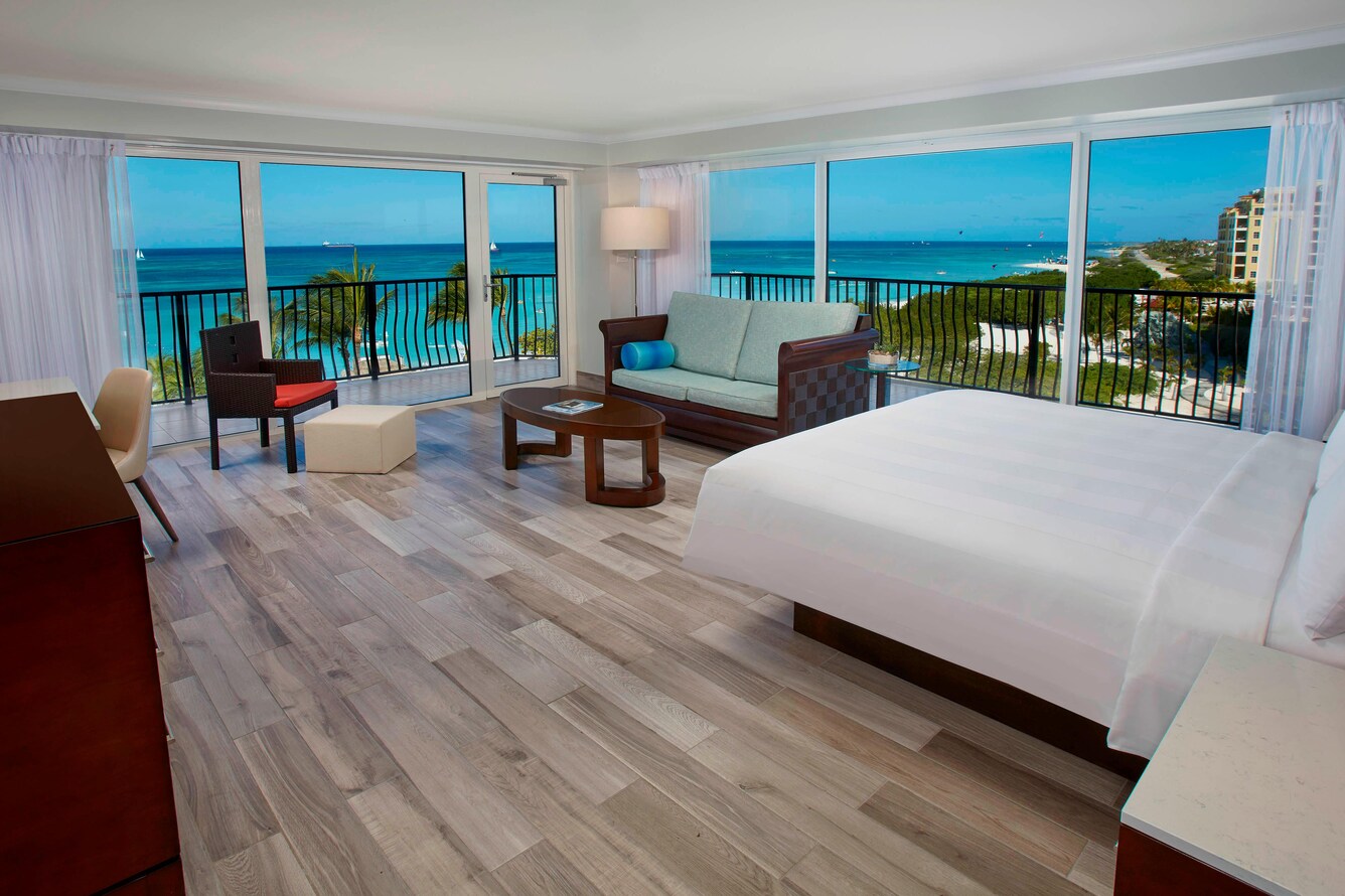 King sized bed in a suite with bamboo flooring and an extra large balcony.