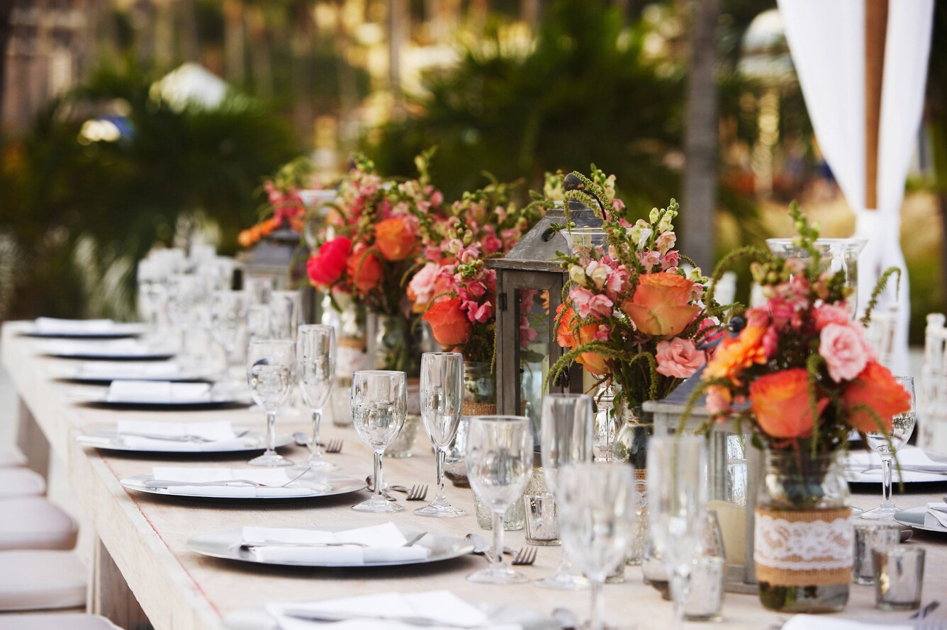 Long table with place settings and flower arrangements prepared for a wedding reception.