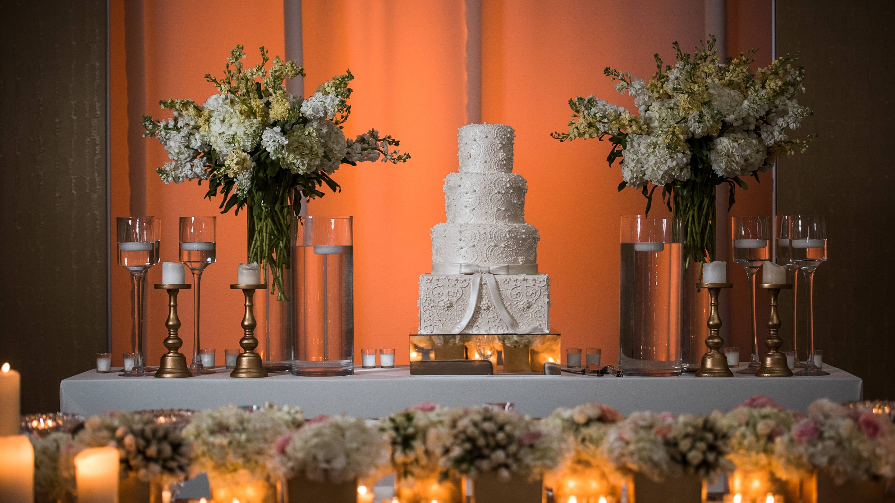 Wedding cake on table between white floral arrangements