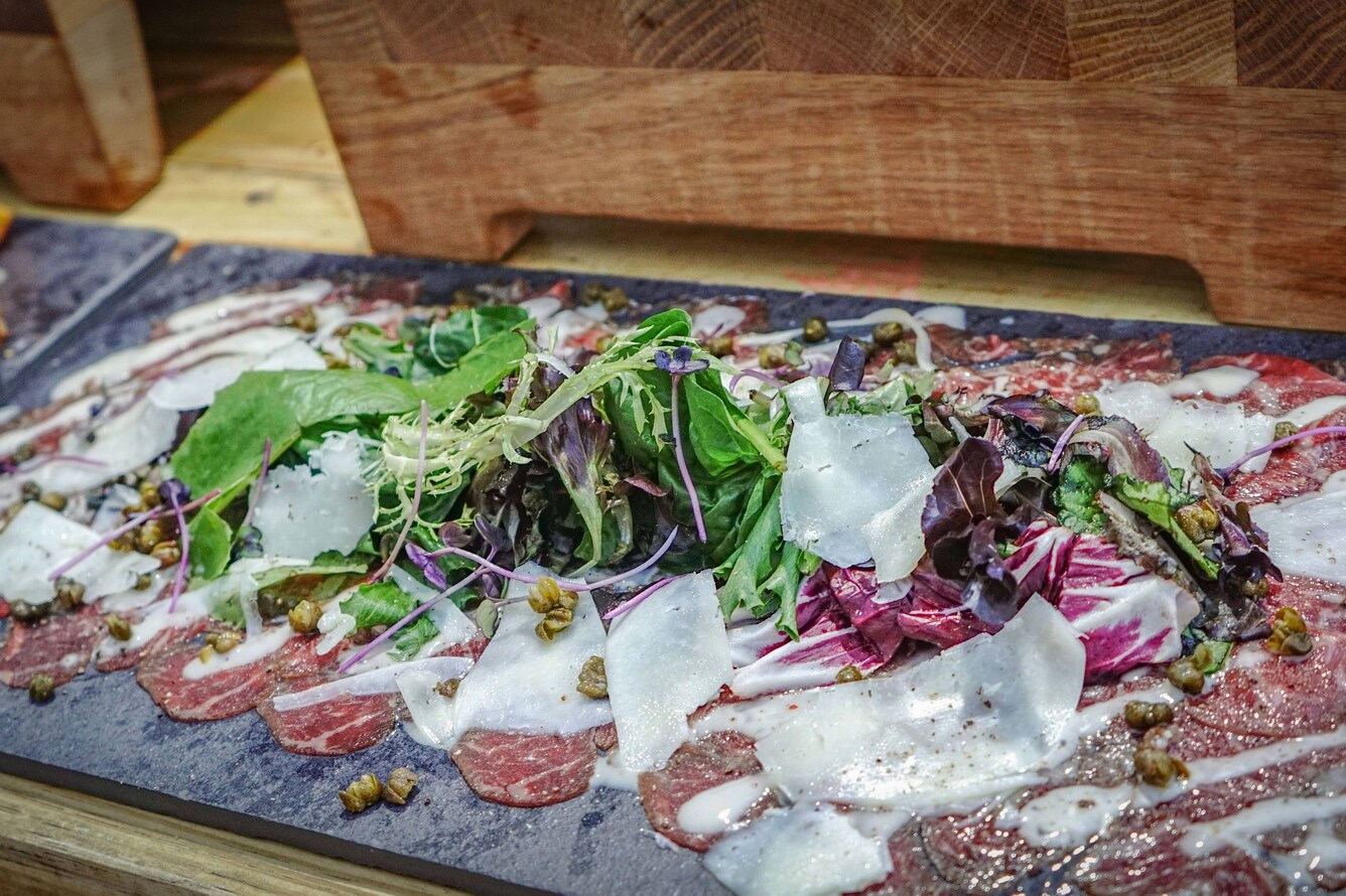 A meat platter with melted cheese and microgreens.